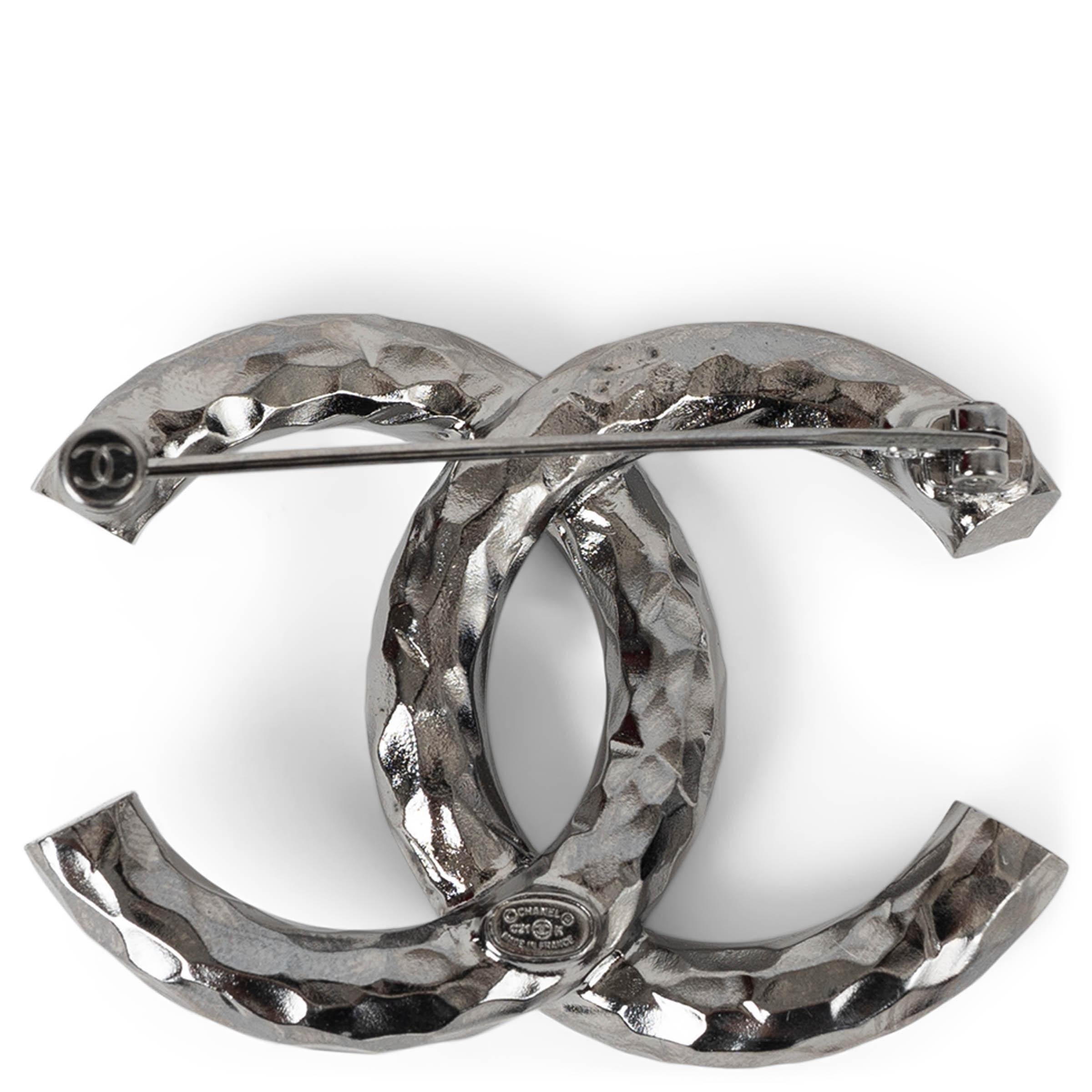 Questa spilla Chanel con cristallo CC grande, autentica al 100%, è realizzata in metallo con finitura in rutenio e presenta un'estetica moderna e tagliente. L'iconico logo CC a incastro è impreziosito da cristalli scintillanti, mentre i lati