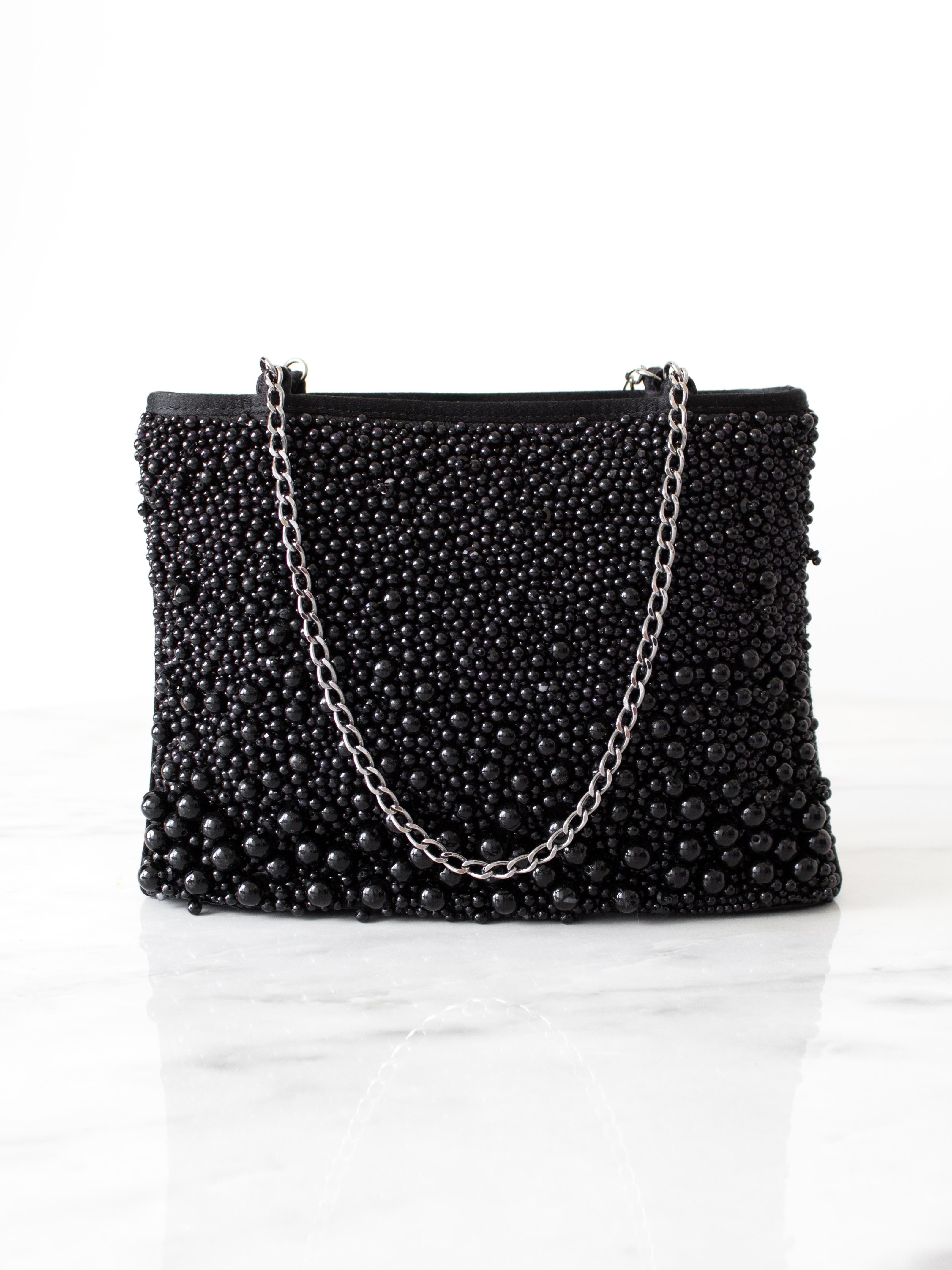 Die schicke Abendtasche aus der Act I-Kollektion Frühjahr-Sommer 2001 von Chanel. Die aus luxuriöser Seide gefertigte Tasche ist mit Ruthenium-Kettenbändern verziert und trägt das ikonische CC-Logo sowie zarte Perlenimitate, die an schwarzen Kaviar