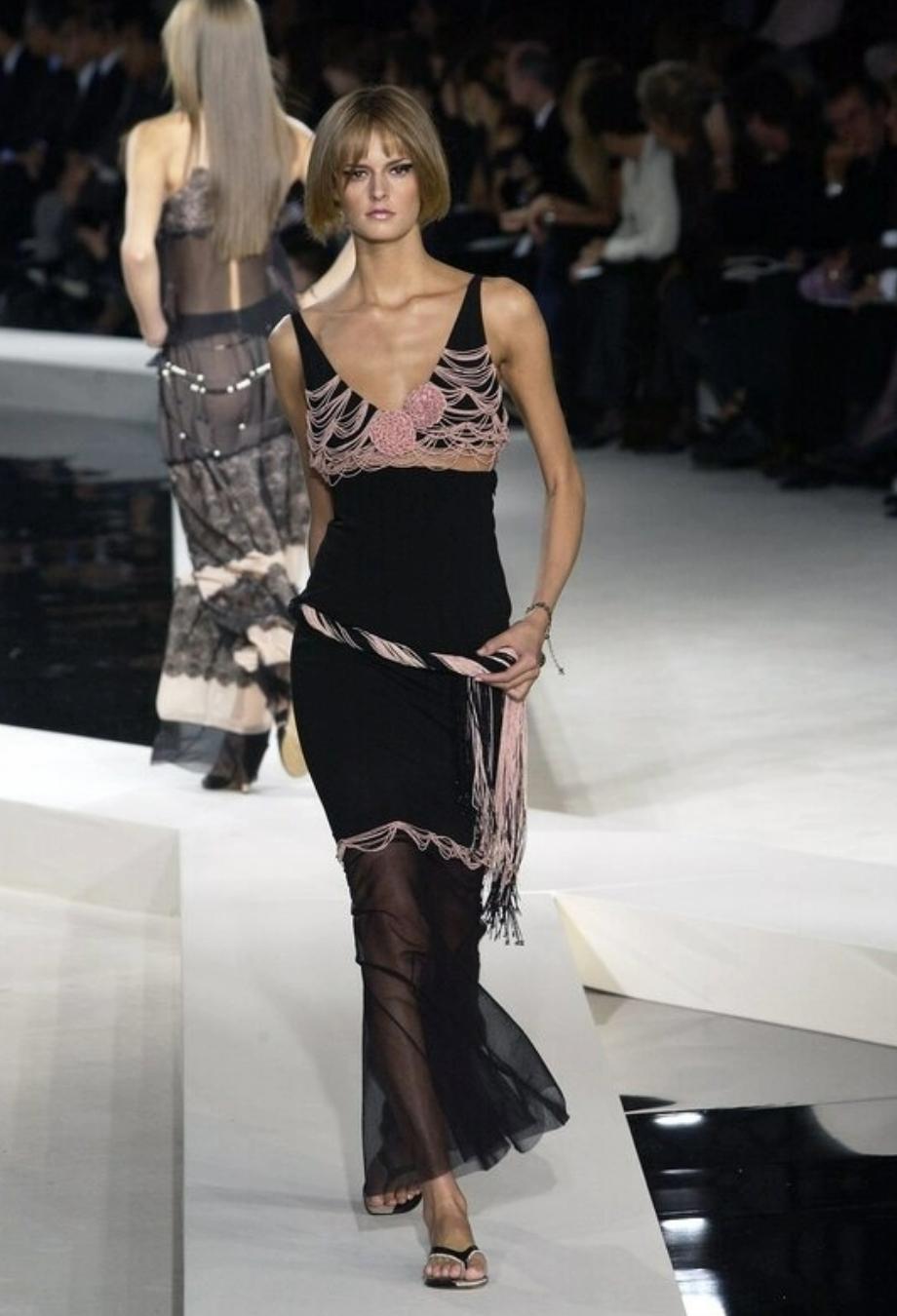 Issue du défilé emblématique printemps/été 2003 de Chanel, cette robe exquise reflète le mélange de romantisme et de modernité propre à Karl Lagerfeld. Confectionnée de main de maître en crêpe noir, la silhouette est taillée pour effleurer le corps