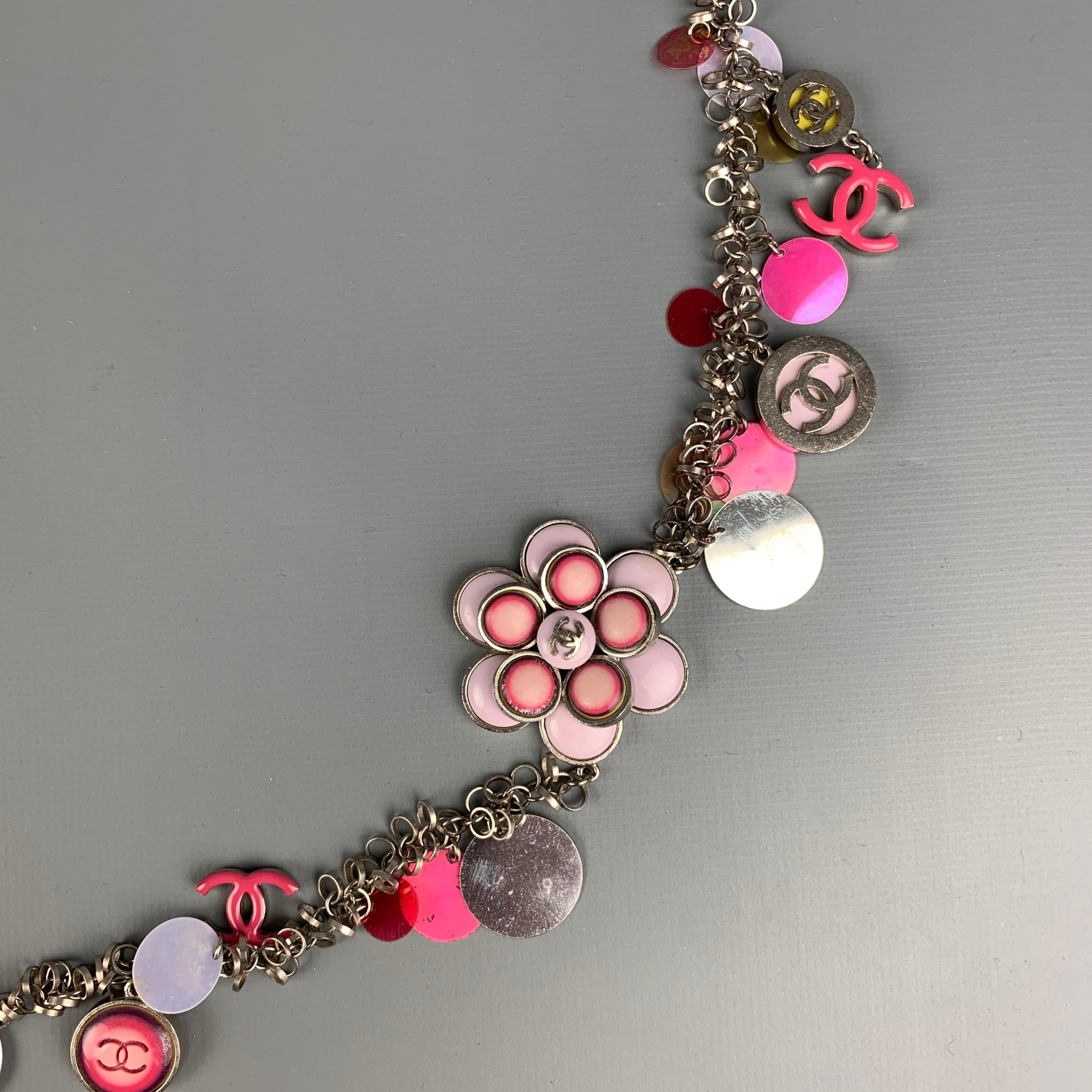 CHANEL S/S 2004 necklace comes in a silver tone metal base featuring a multi-color circular plastic medallion discs, CC charms, one large camellia flower detail, and a clasp closure. 

Very Good Good Pre-Owned Condition.

Marked: