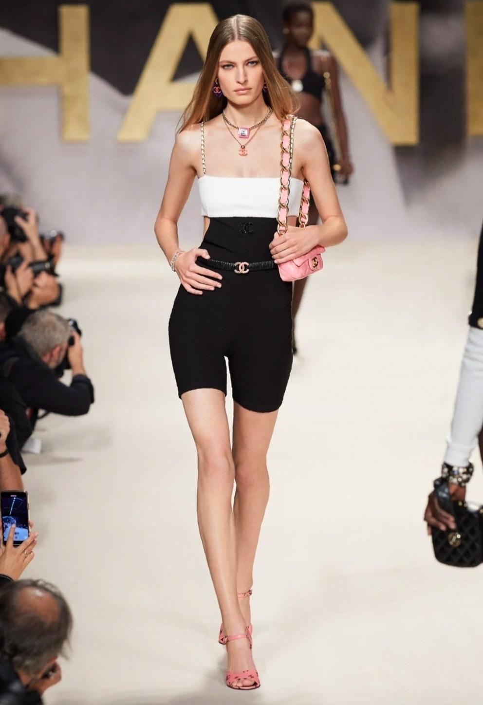 Introducing the most coveted piece from the Chanel Spring/Summer 2022 collection: the black and white short jumpsuit as seen on runway look #7. This stunning jumpsuit is crafted from luxurious black and white stretchy crepe with exquisite gold chain