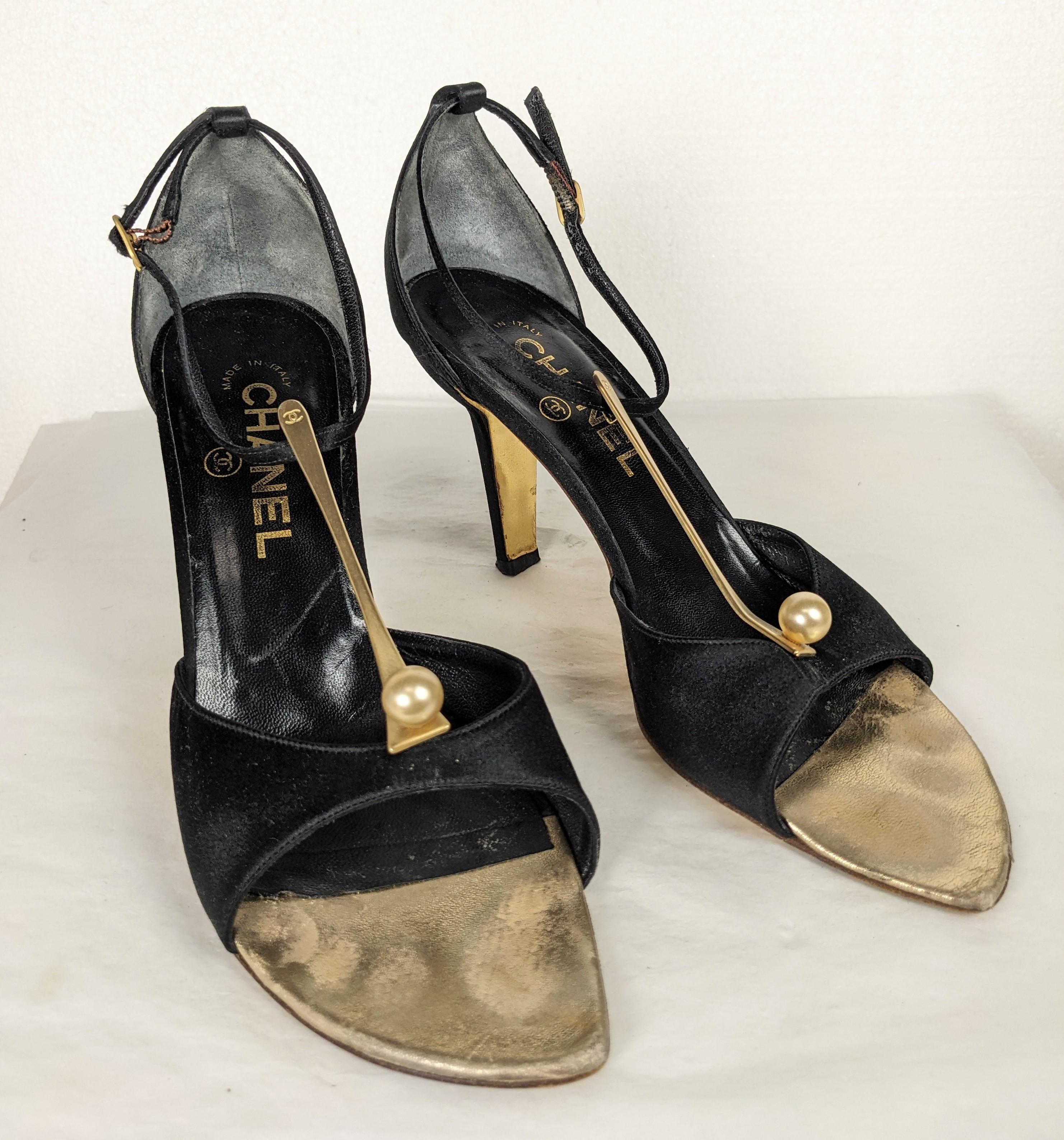 Elegant Chanel Satin and Pearl T Strap Evening shoes from the 2000's Karl Lagerfeld. A matte gold T has Chanel logo and faux pearl at base. Black silk satin unusual coupe shaped heel. Elongated gold kid sole comes to a point at toe. Size 37.5.