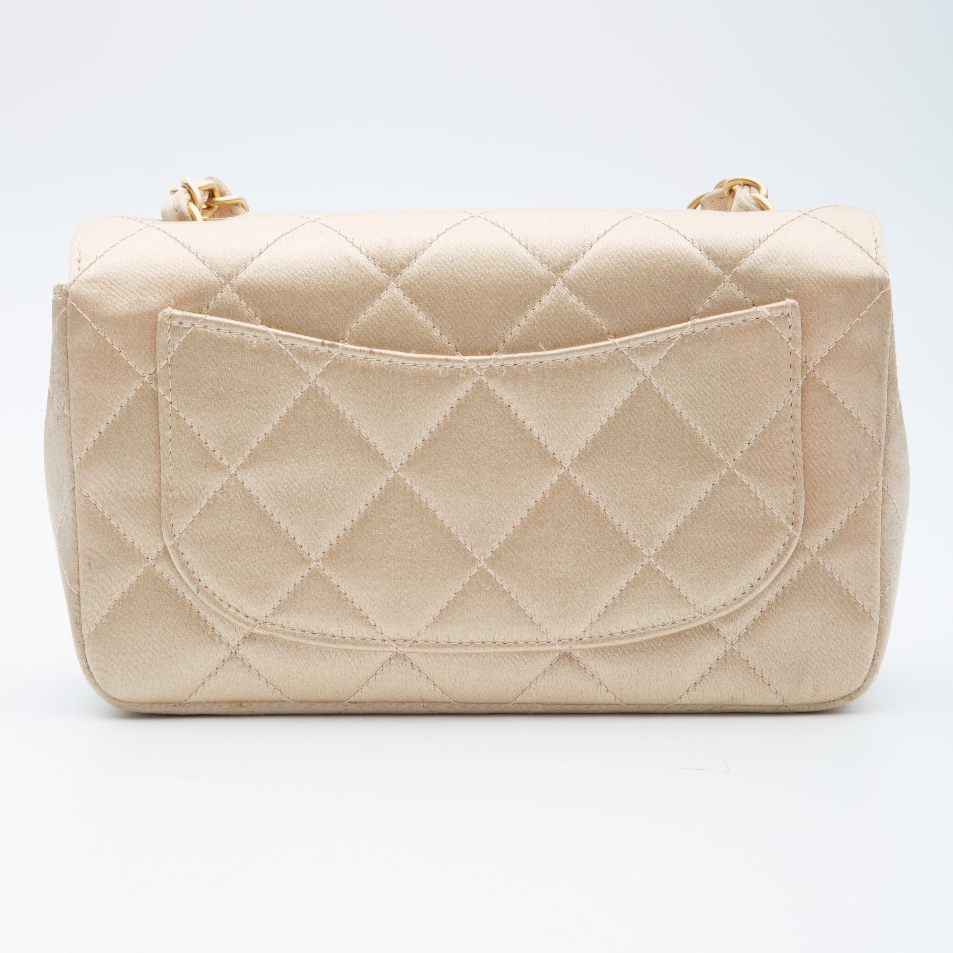 This rectangular classic mini flap bag is made with satin in light gold. The bag features two top holes for the shoulder straps (verse traditional four holes), a gold tone chain interlaced with leather shoulder strap, interlocking CC twist lock