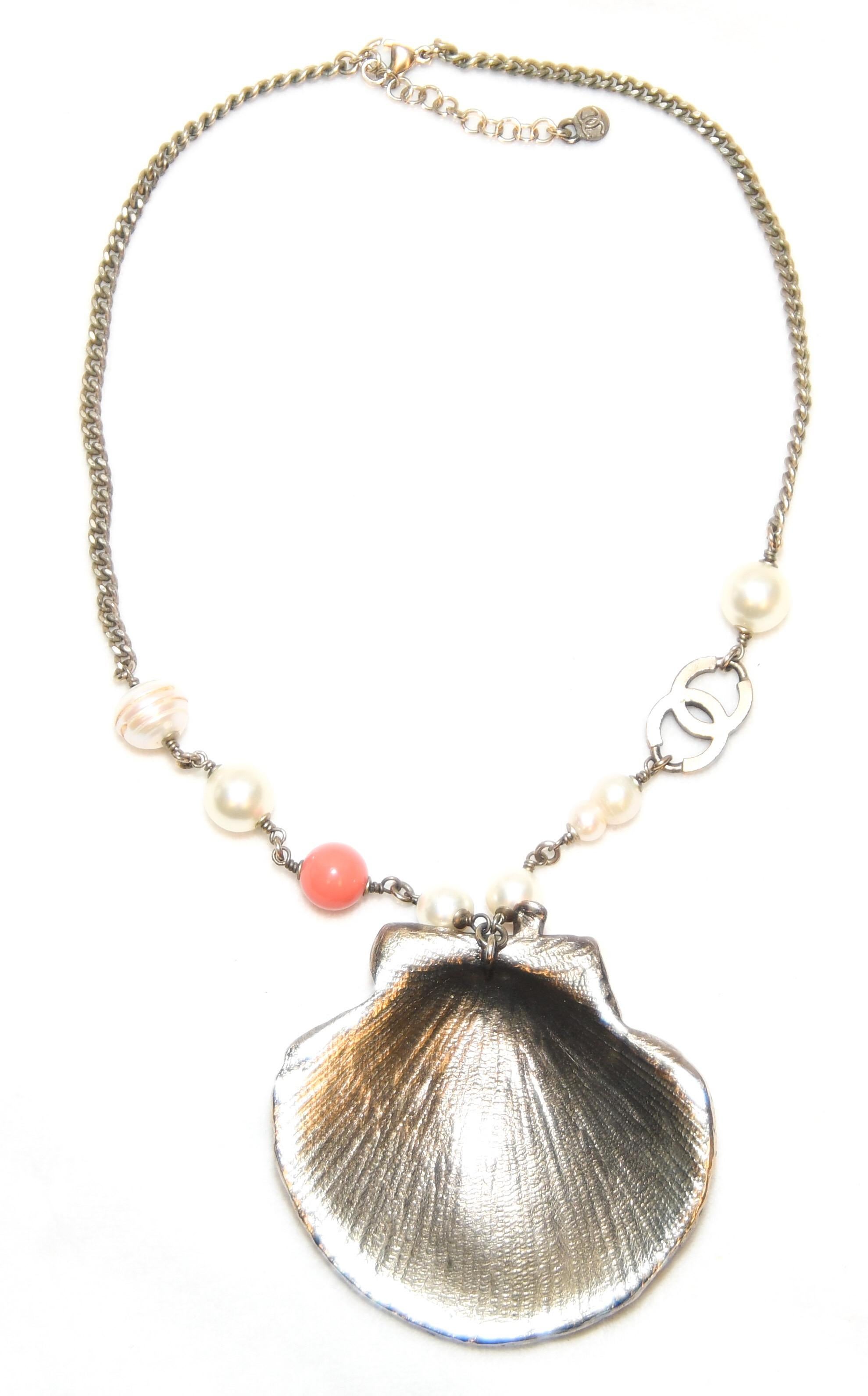 Distinctly Chanel!  Focal point features a Scallop shell adorned with bezel set crystals, crystal CC logos, a turbo star shell and a spiral cone shell each with crystals.  A coral branch enhanced by crystals is the focal point.  One coral bead