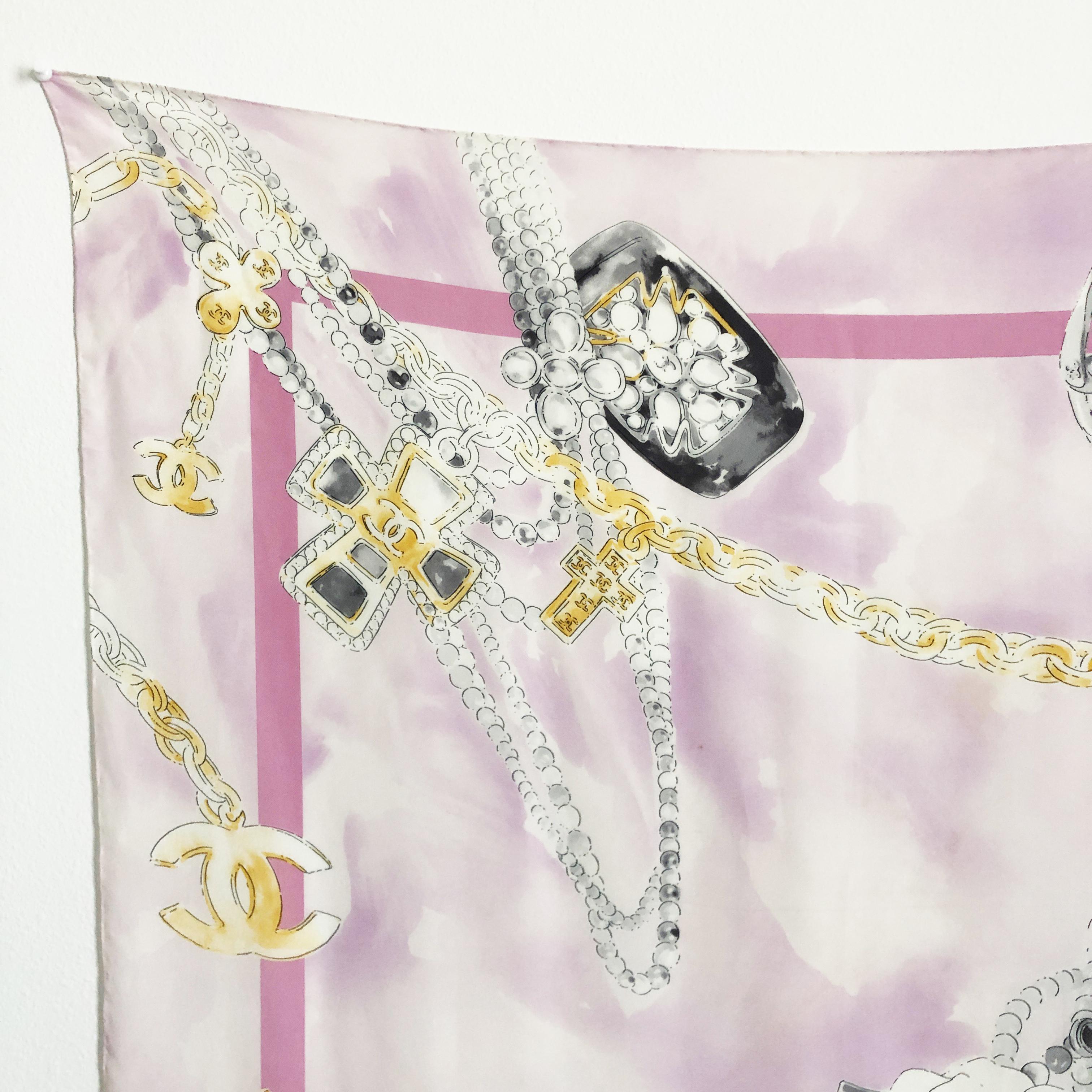Authentic, preowned Chanel silk scarf or shawl with a bijoux or jewelry motif, likely made in the late 90s.  Made from silk, it features Chanel's iconic jewelry designs with chains, the CC logo, pearls and bracelets. 

Gorgeous colors on this one,