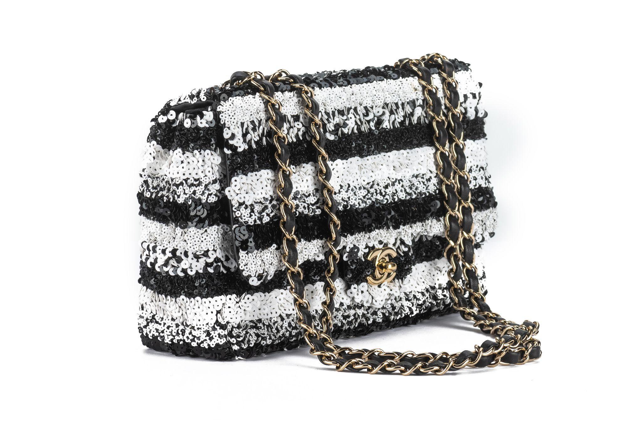 This Chanel Sequin Classic Small Flap in Black and White. This small sleek flap bag is beautifully crafted with the layering of small and large black and white sequins that create the entire surface of the bag. The elegant handbag features polished