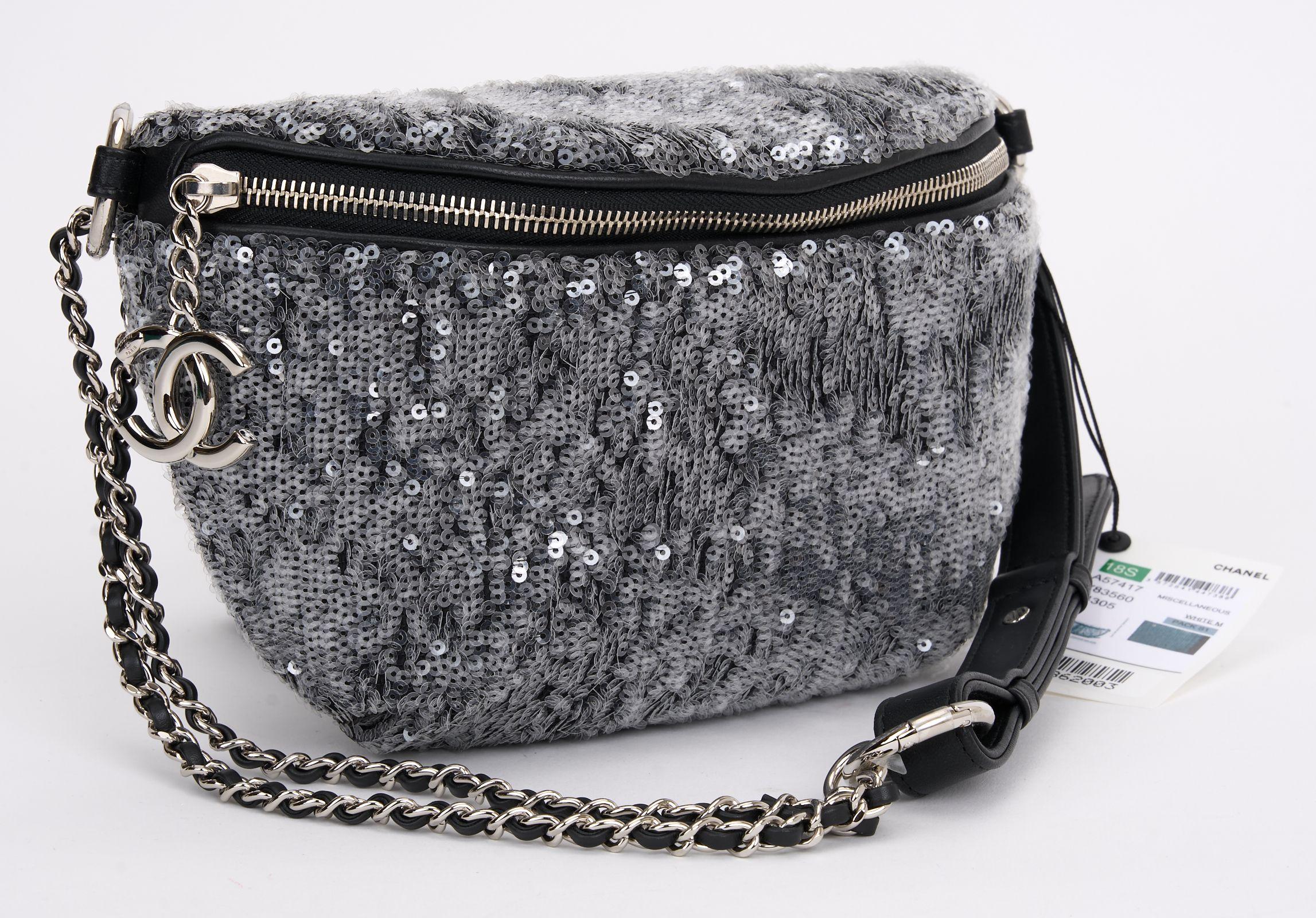 This Chanel Sequin Waist Bag Fanny Pack in silver and black features finely crafted silver sequins with a black undertone and a silver leather threaded chain link, leather belt strap/ waist strap with adjustment links. A top zipper pocket with a