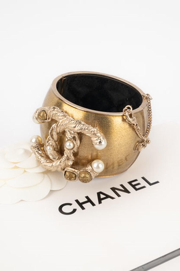 Chanel - (Made in France) Bracciale da polso in metallo dorato con paillettes, ornato da un imponente logo cc. Prototipo di gioiello.

Informazioni aggiuntive:
Condizioni: Ottime condizioni
Dimensioni: Circonferenza: 17 cm - Altezza: 4,5