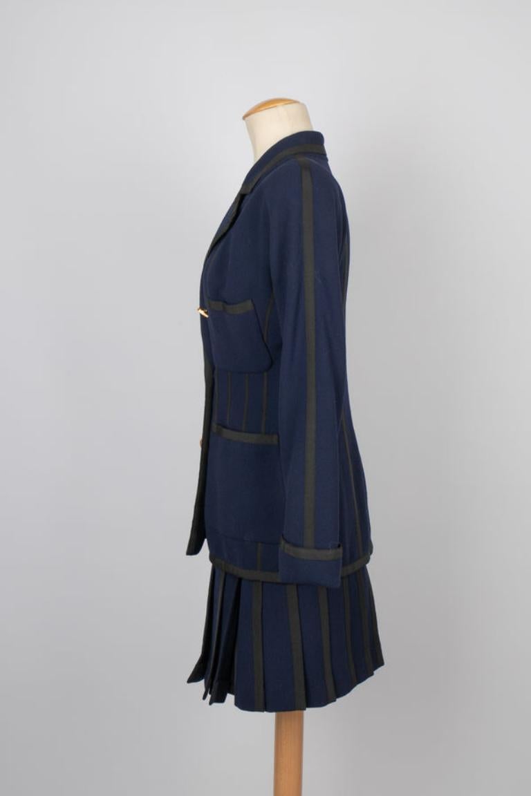 Chanel - (Made in France) Ensemble tailleur composé d'une veste et de deux jupes en crêpe de laine bleu marine bordées de galons noirs. L'ensemble est vendu avec la casquette de style marin. Collection Haute Couture Printemps-Eté 1991.

Informations