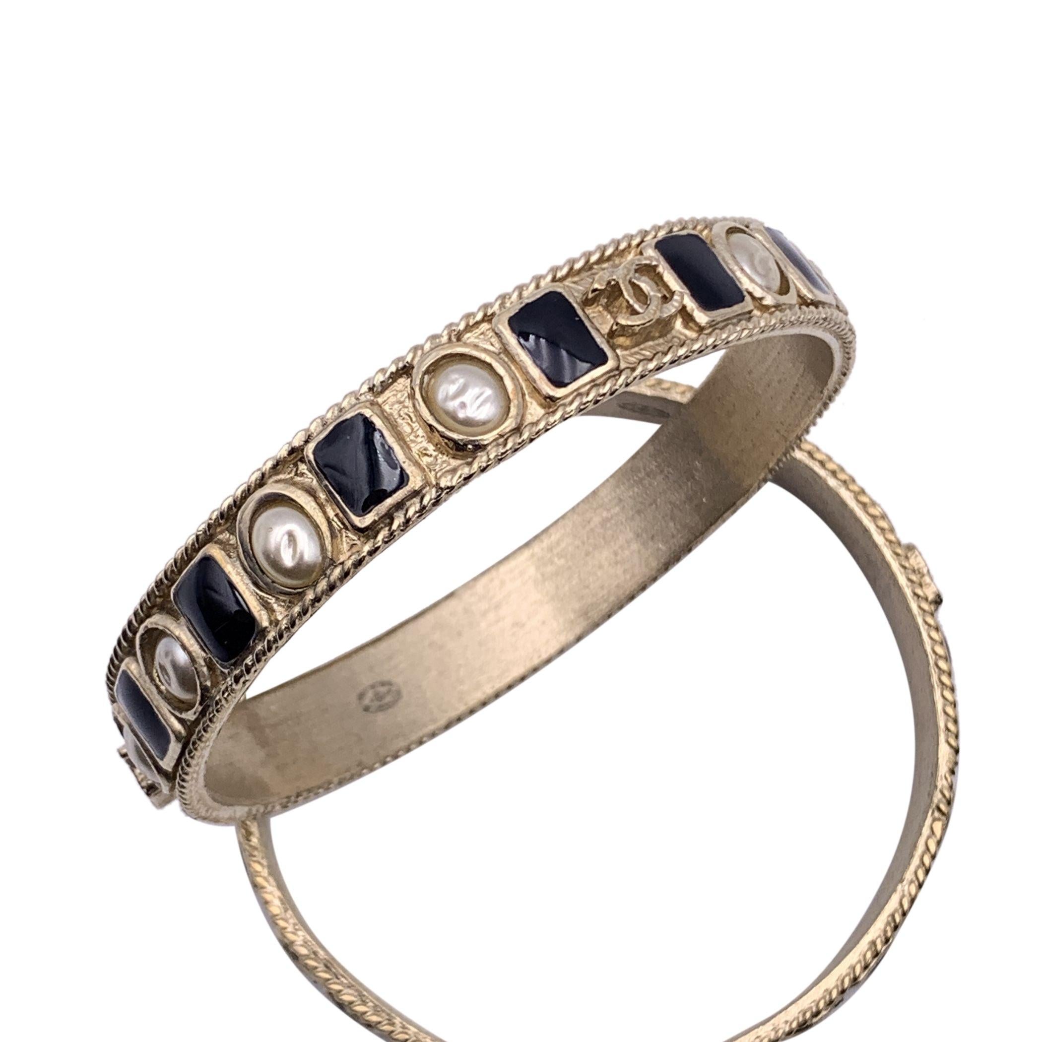 Lovely set of 2 bangle cuff bracelets by CHANEL. Gold metal with black enamel and artificial pearls embellishment. CC logos accents. Stamped 'Chanel B11 CC P - Made in Italy' oval mark stamped internally. Will fit up to approx. 7.5 inches - 19 cm