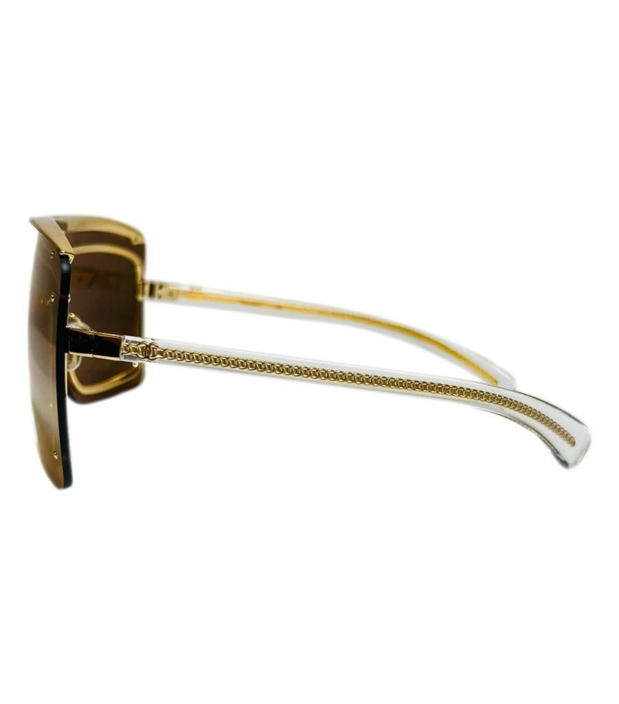 Chanel Shield verspiegelte Sonnenbrille mit Kette und 'CC' Logo-Bügeln

Goldfarbene, maskenförmige Sonnenbrille mit umlaufenden Gläsern und goldenen Nieten auf der Vorderseite sowie einem eingravierten Metallbügel mit der Aufschrift Chanel