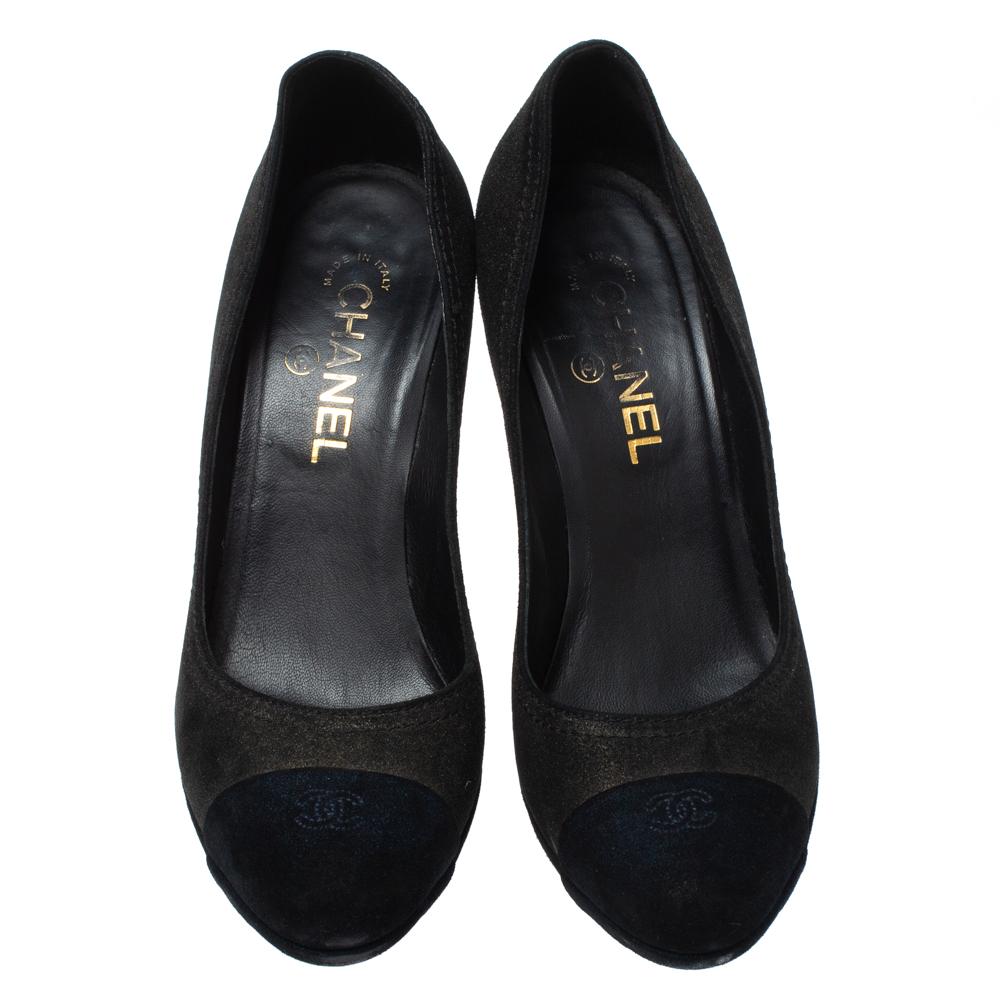 These shimmery black pumps from Chanel have been crafted from suede and styled with navy blue cap toes. They flaunt CC logos on the toes and come endowed with high heels, comfortable leather-lined insoles and solid platforms.

Includes: Branded Box

