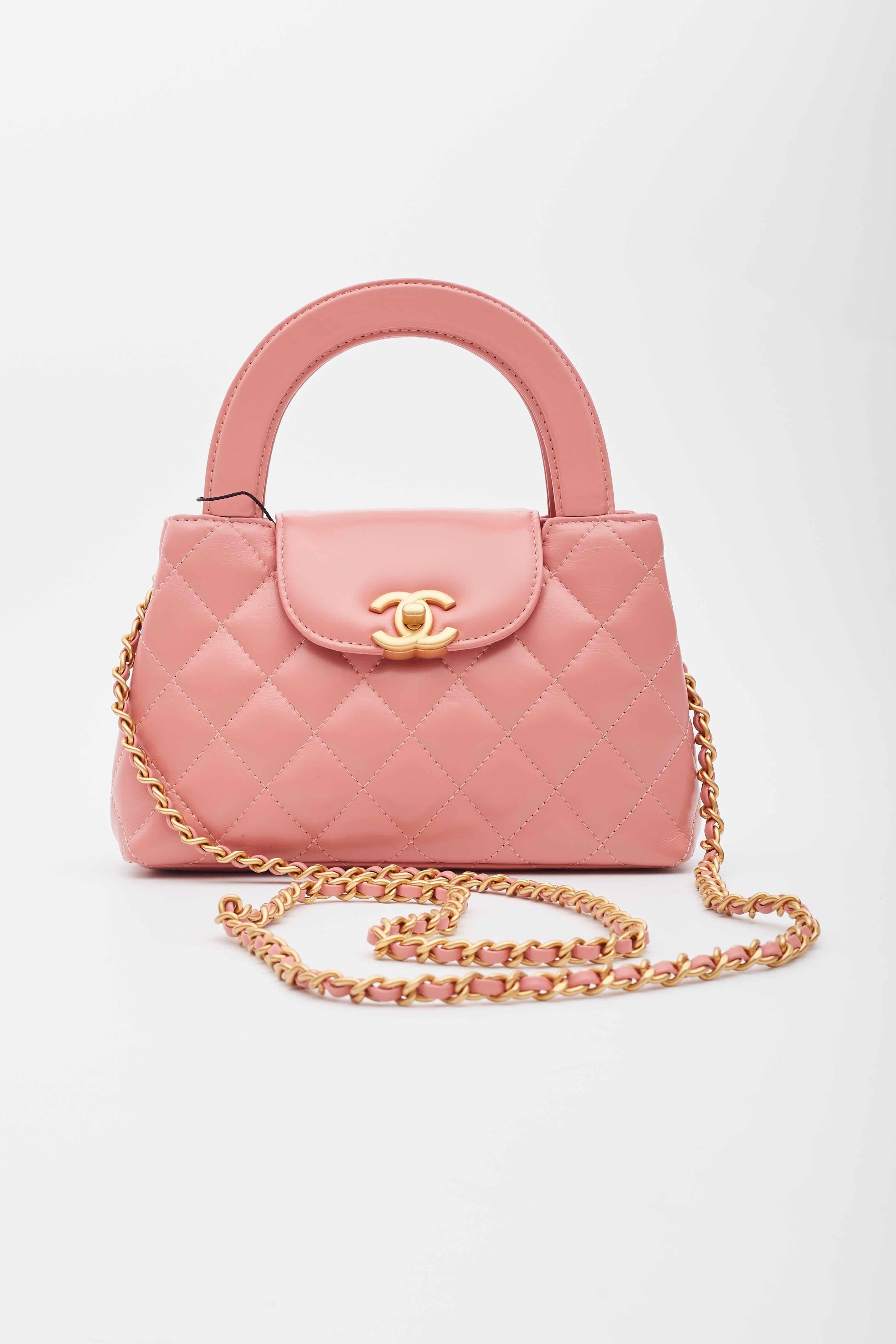 Chanel Top Handle Bag. From the Fall/Winter 2023 Collection by Virginie Viard. This mini bag is a twist on an archival Chanel bag, featuring a long crossbody chain strap. This dual top handle bag is quilted in shiny aged calfskin leather in pink,