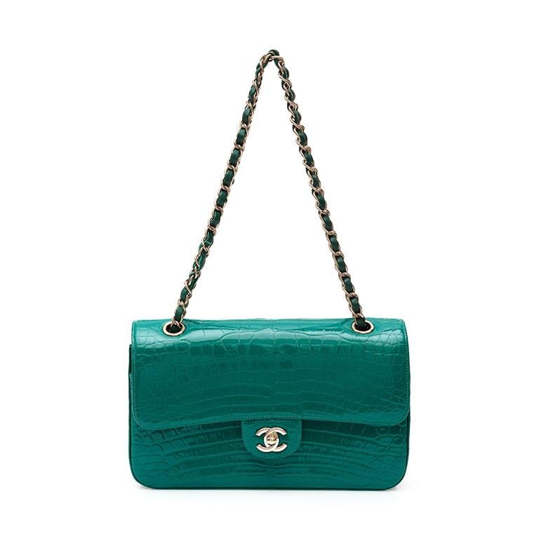 Crafted in France from exotic alligator leather in a highly sought after shade of emerald green, this iconic flap bag by Chanel is finished with the classic CC turn-lock in silver-tone hardware and features a fold-over top, a main internal