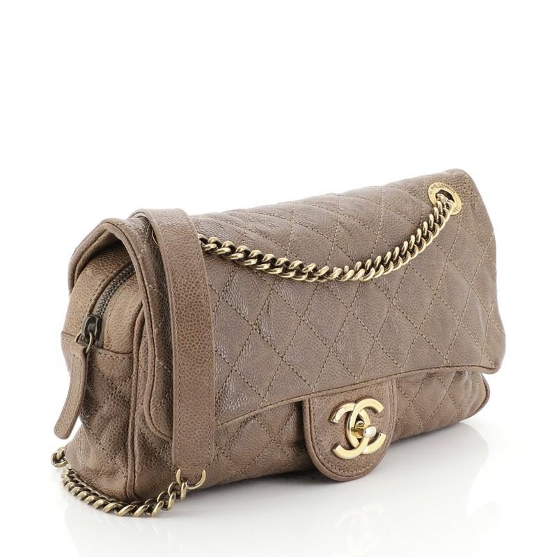 This Chanel Shiva Flap Bag Quilted Caviar Large, crafted in brown quilted caviar leather, features chain link strap with leather pad and aged gold-tone hardware. Its CC turn-lock closure opens to a red fabric interior with zip and slip pockets.