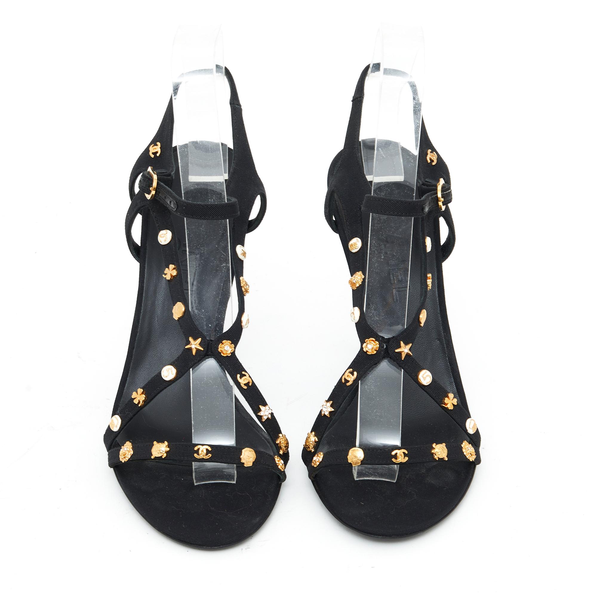 Chanel sandals composed of thin black canvas straps (lined with leather) adorned with mini Chanel icons in gold metal and rhinestones or ivory enamel for some: camellia, Coco, CC, 5, star, ... Size 37.5FR, heel 10.5 cm , insole 23.7 cm. The sandals