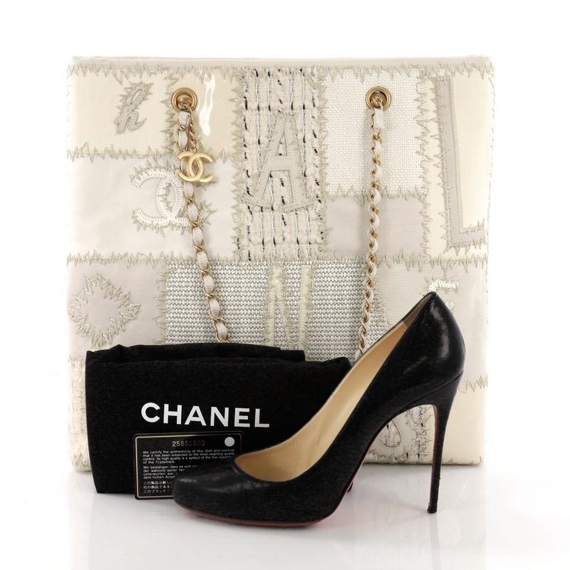 This Chanel Shopping Tote Mixed Media Patchwork Small, crafted from off-white mixed media patchwork, features dual woven-in chain straps and gold-tone hardware. Its magnetic snap button closure opens to an off-white fabric interior with zip and slip
