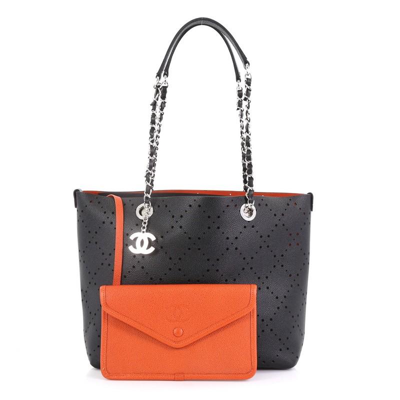 This Chanel Shopping Tote Perforated Caviar Small, crafted in black perforated caviar leather, features woven-in leather chain straps with leather pads and silver-tone hardware. It opens to an orange microfiber interior. Hologram sticker reads: