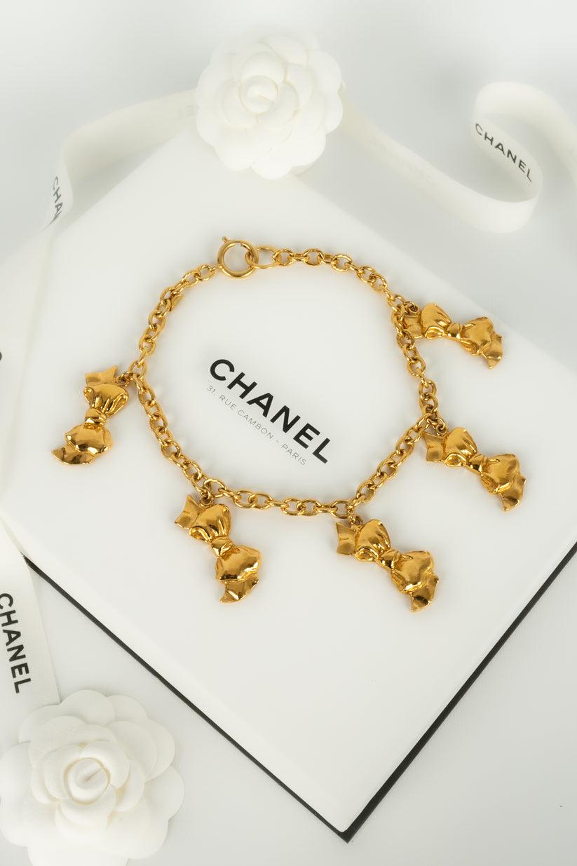 Chanel - (Made in France) Kurze Halskette aus vergoldetem Metall mit Anhängern, die Schleifen symbolisieren. Schmuck aus den Anfängen der 1990er Jahre.

Zusätzliche Informationen:
Abmessungen: Länge: 39 cm
Zustand: Sehr guter Zustand
Sellers