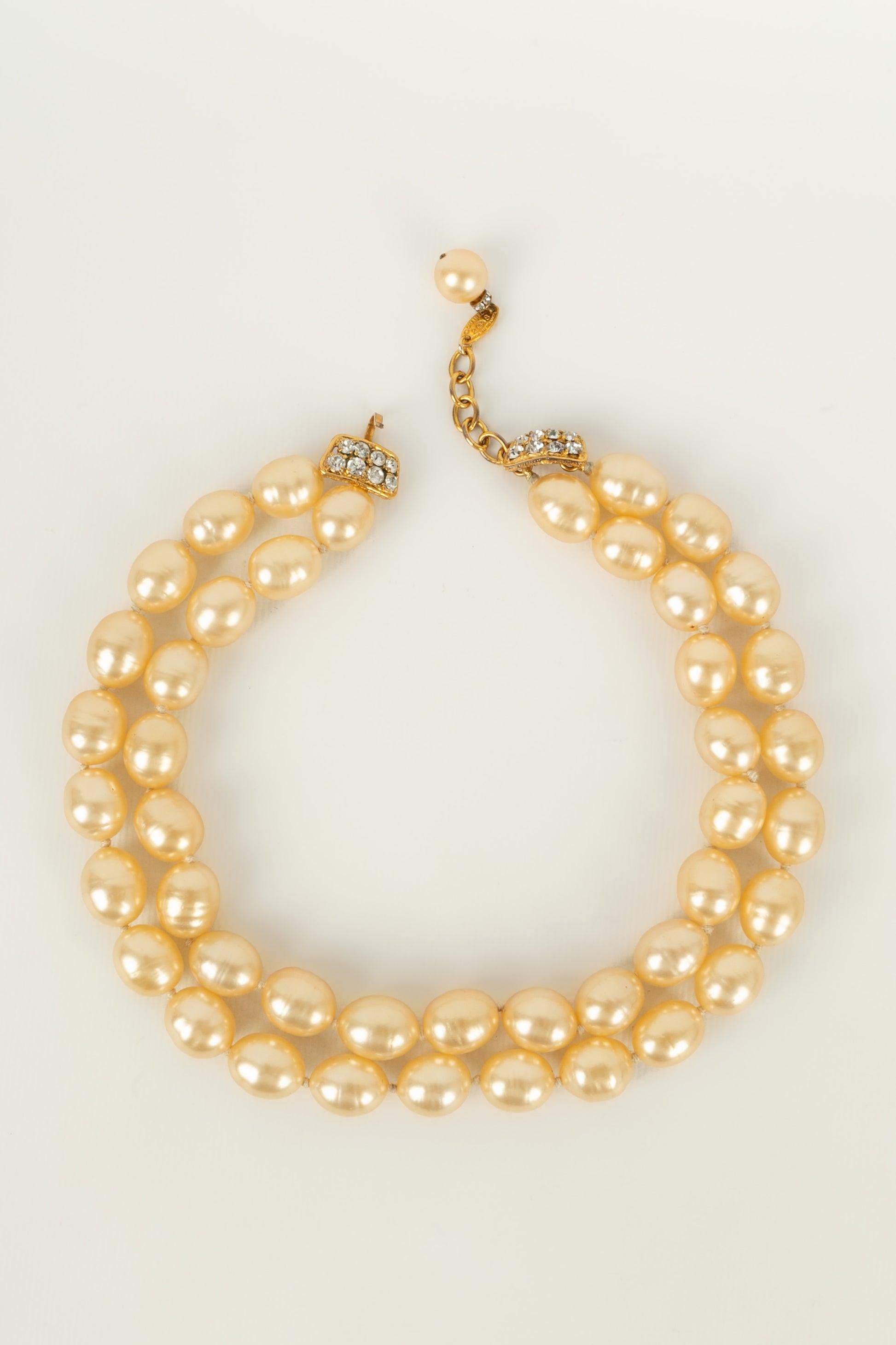 Chanel - (Made in France) Kurze zweireihige Halskette aus Perlen, die mit Knoten und einem Anhänger aus vergoldetem Metall, Glaspaste und Strasssteinen zusammengesetzt sind. Collection'S 2CC8.

Zusätzliche Informationen:
Zustand: Sehr guter