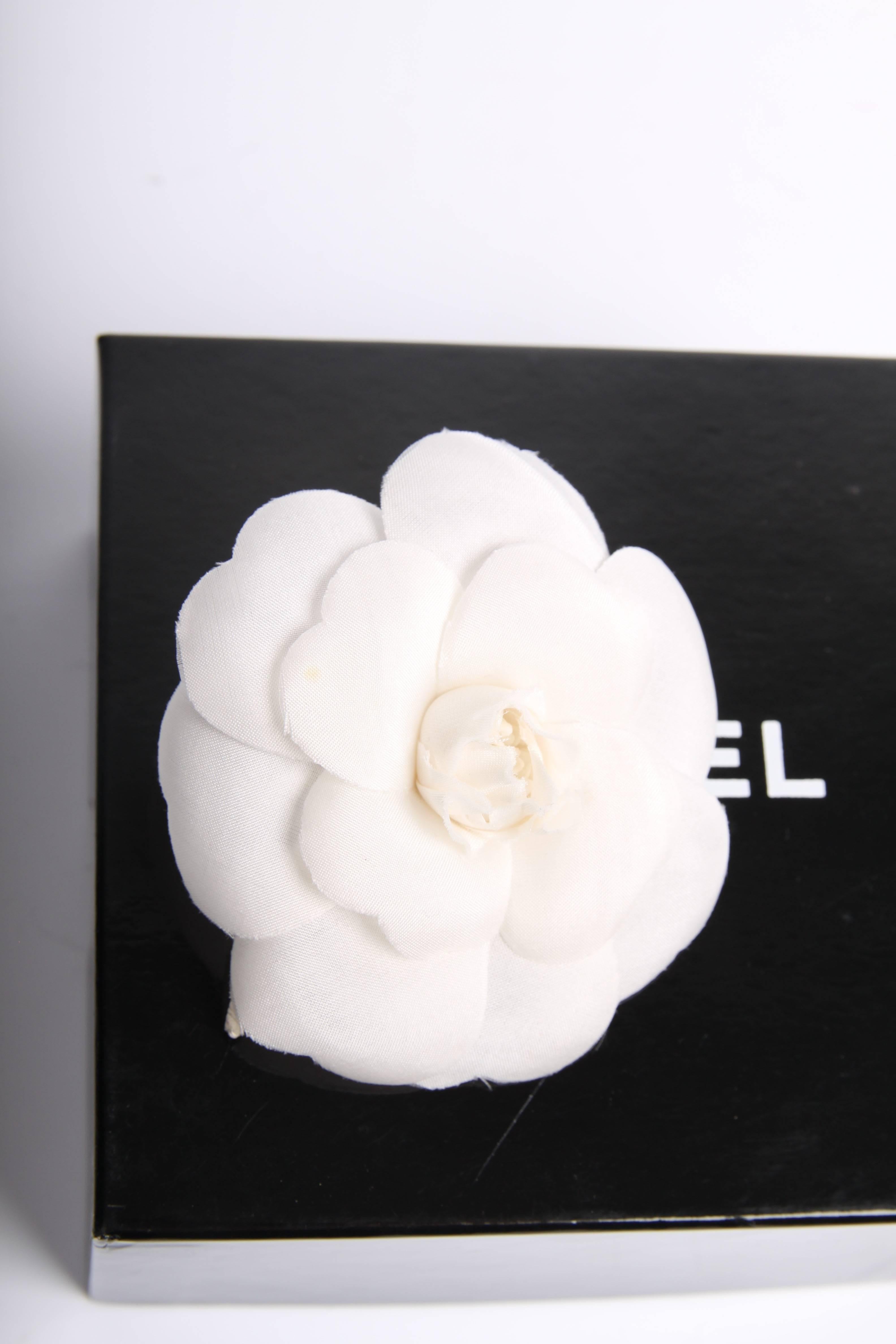 This one is fantastic! A silk camellia flower, known as the signature of Chanel, to be worn as a brooch!

The intersection is 7,5 centimeters, it is a real statement on your blouse or the lapels of your jacket. Fully made of white silk, 7 large