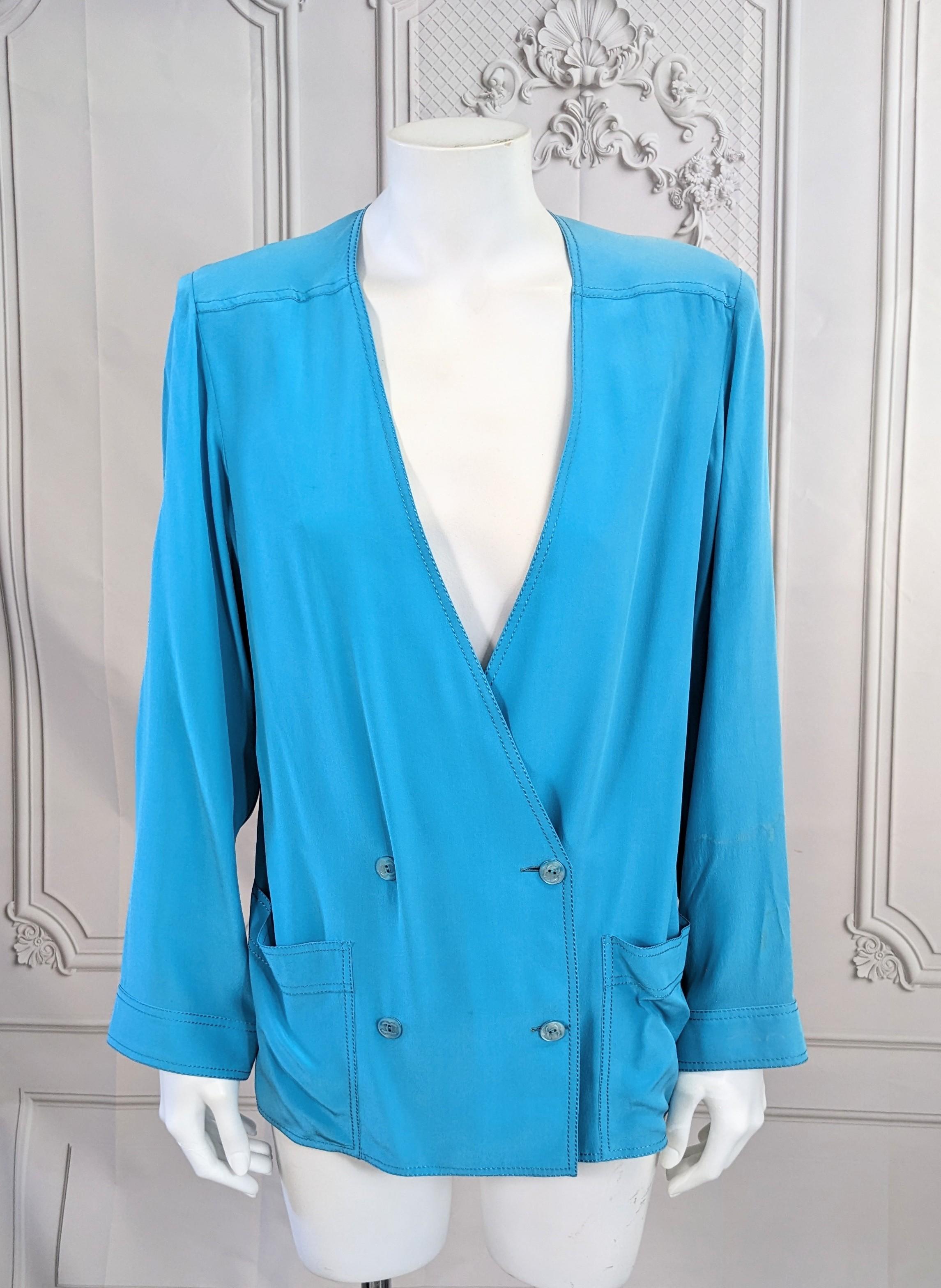 Chanel Turquoise Silk Crepe Blouse styled as a double breasted jacket. Can be worn as a blouse or an outer layer as well. Turquoise silk crepe with heavy silk topstitching and CC Mother of pearl buttons. Straight boxy cut. 1970's France. 