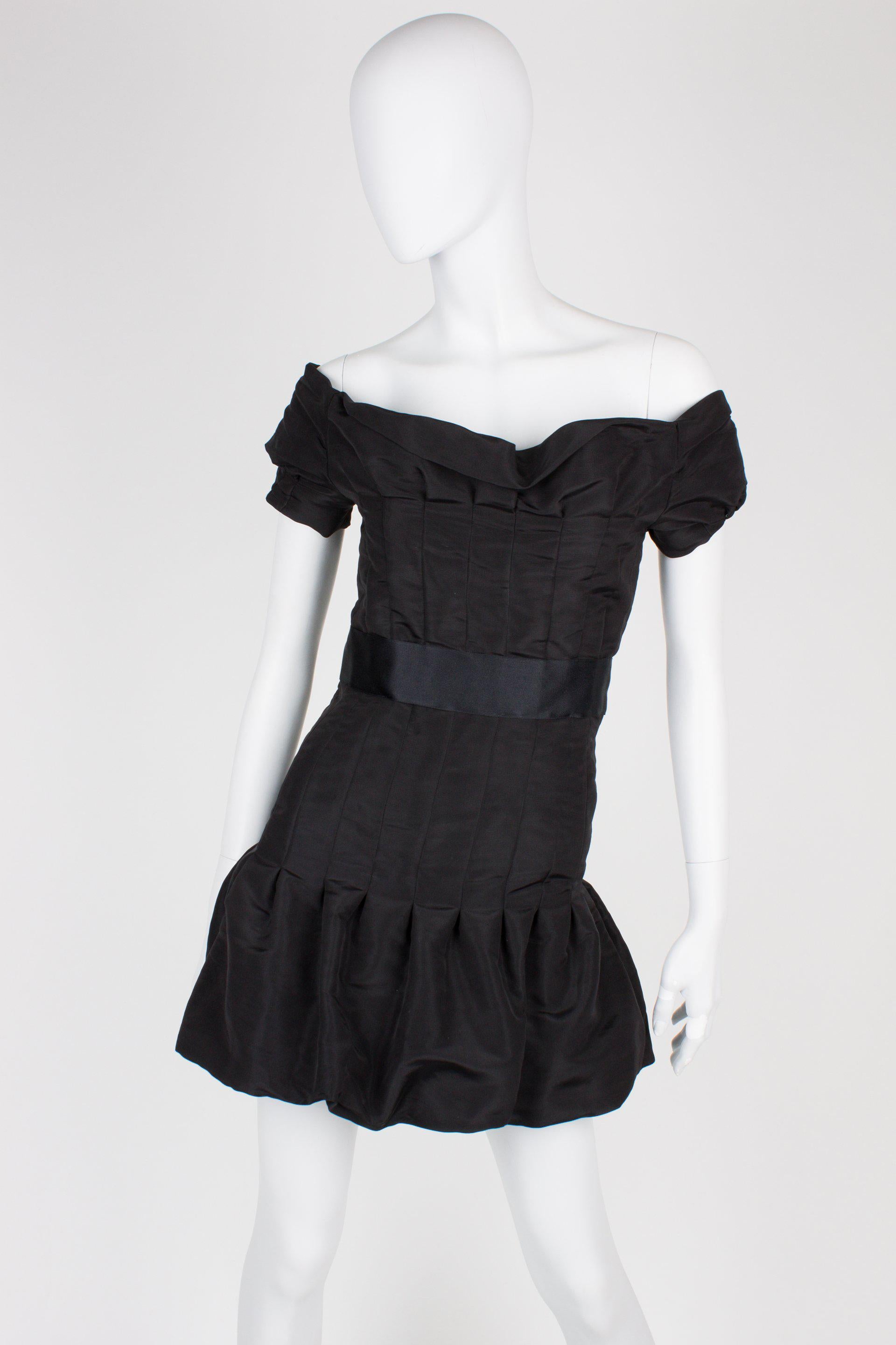 Adembenemend mooi jurkje van Chanel uit de Runway Collectie van 2005.

Off-shoulder dress met een kort mouwtje en een brede glanzende zijden band in de taille. Sluiting op de achterzijde met negen zwarte drukknopen met CC-logo in het