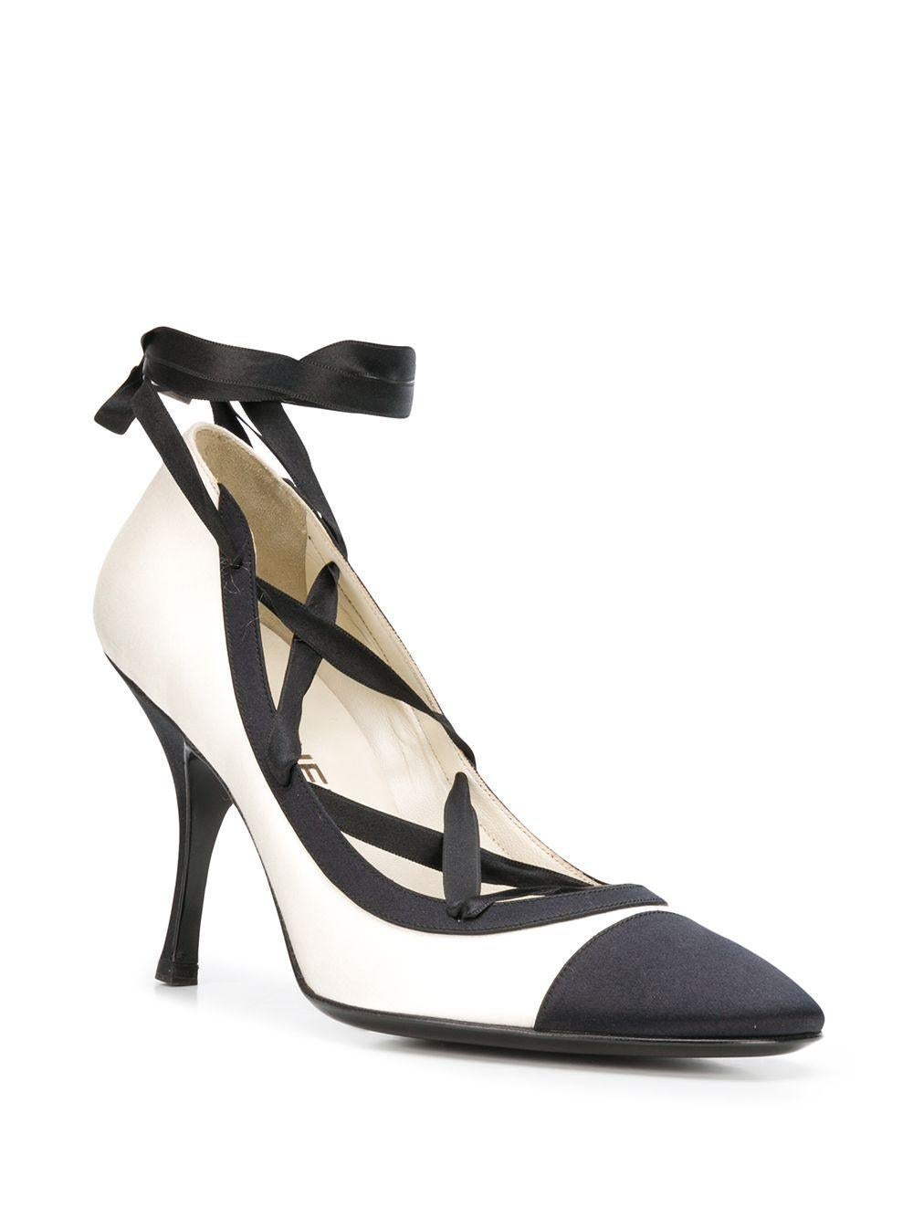 Crafted in Italy from a combination of smooth black and cream silk, these vintage pumps by Chanel are for the fashion forward, featuring a mid high stiletto heel, a rounded almond toe and an elegant leather lace-up front fastening. These contrasting