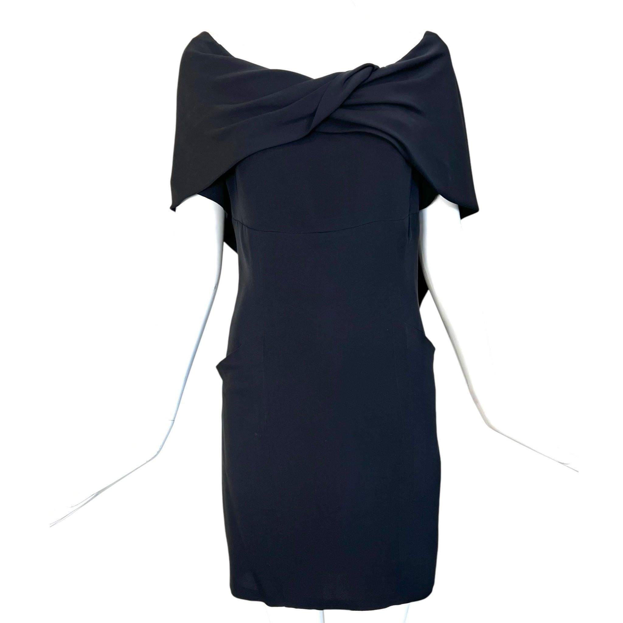 Elegant, silk little black dress by Chanel Boutique. Circa mid 90s. The chic illusion of an off the shoulder silhouette without all the fuss, due to the expert tailoring. Delicately draped matte silk crepe twists at the front bodice leaving the