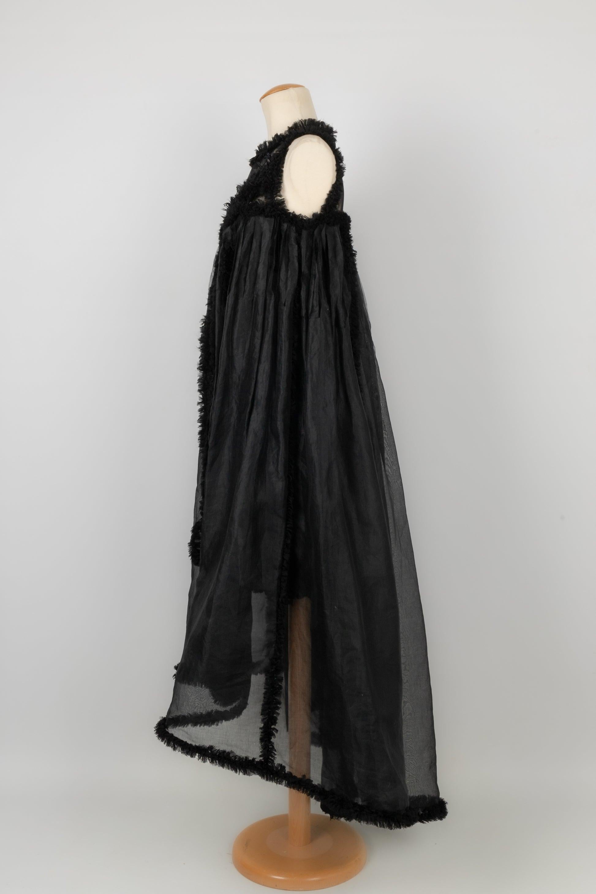 Chanel - (Made in France) Schwarzes Kleid aus Seidentaft, mit Federn genäht und auf der Vorderseite in zwei Seiten geteilt, Öffnung für ein kürzeres Kleid. Größe 36FR.
Collection Prêt-à-Porter Printemps-Eté 2011 sous la direction de Karl Lagerfeld.
