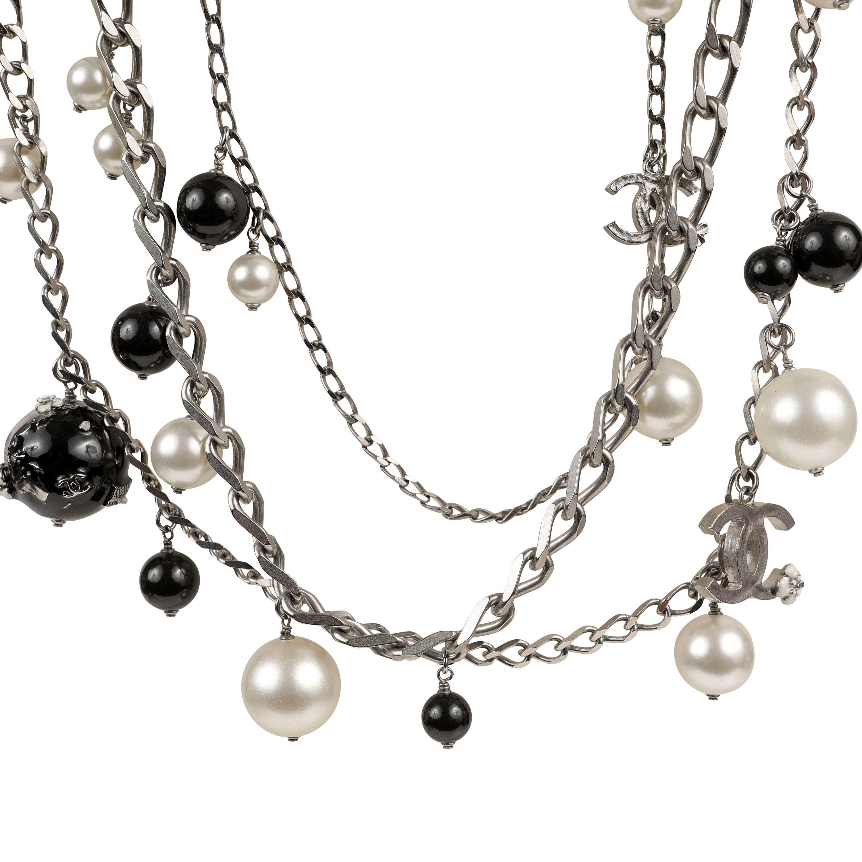 This authentic Chanel Silver Beaded Pearl Charm Necklace Belt is in excellent condition.  Triple layer of silver chains with dangling faux pearls, CC charms, black beads and flower applique globes.   Adjustable length with dangling CC charm.  Pouch