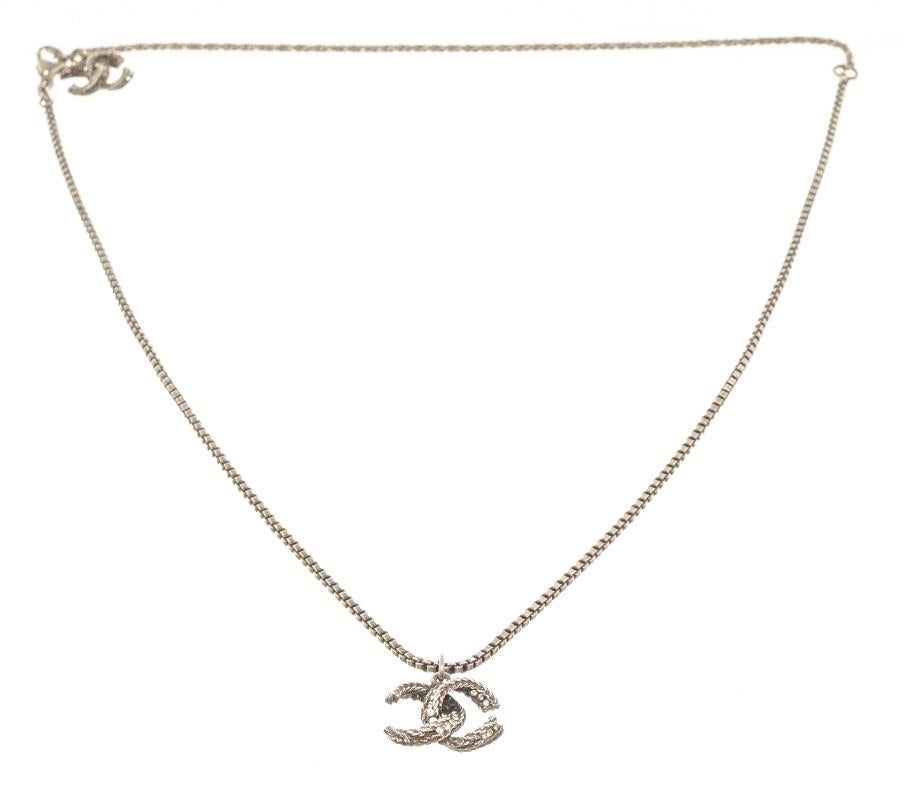 Chanel silver CC chain necklace features a silver-finished body, lobster claw closure with the Chanel stamp on it, a CC logo with rhinestones on it at the end of the chain, and a CC twist logo pendant with rhinestones on it.

57905MSC