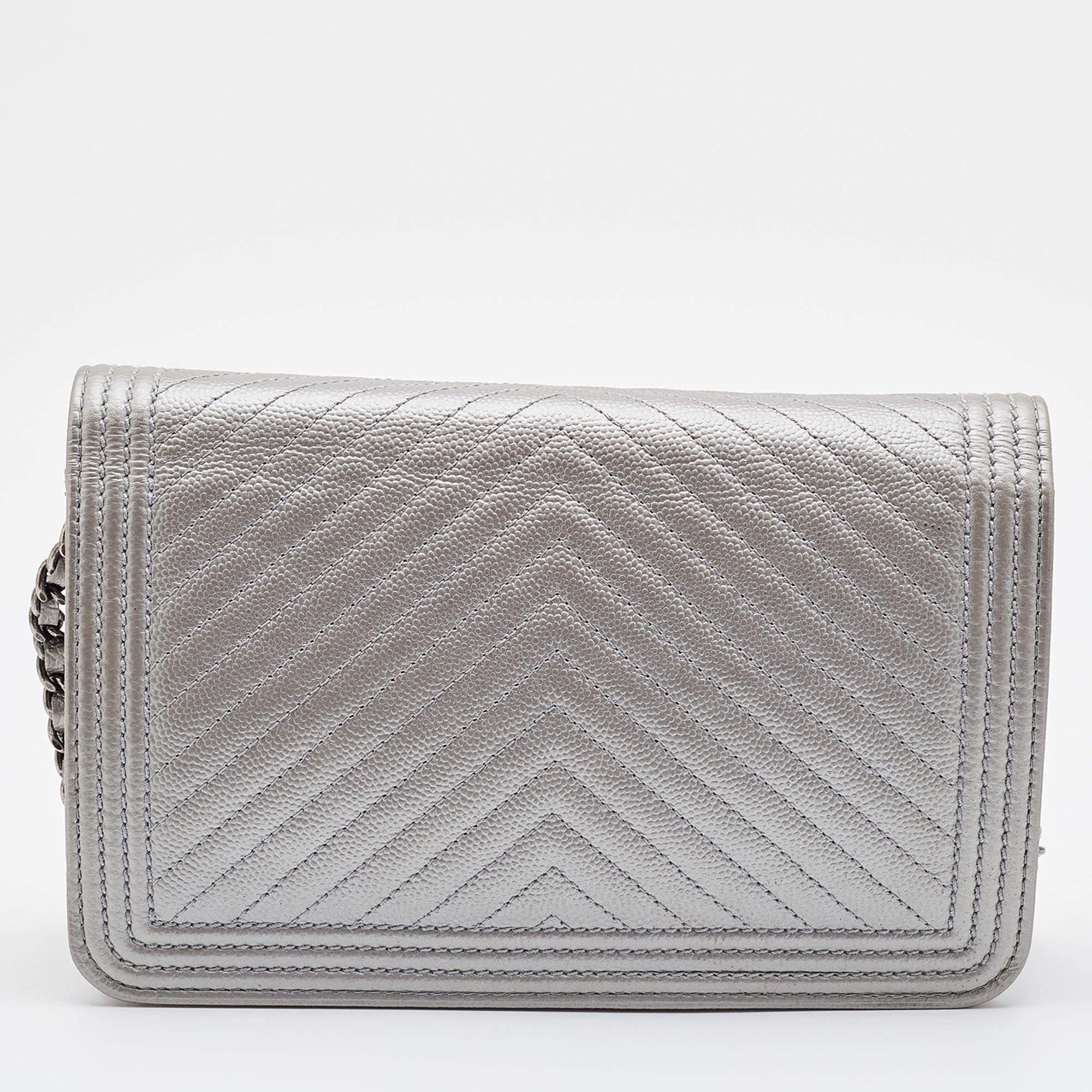 A WOC version of an iconic design, this Chanel Boy bag is beautifully crafted using chevron Caviar leather, and it has recognizable details. The exterior is covered in silver, and the flap is adorned with the CC logo lock. The Boy WOC is complete