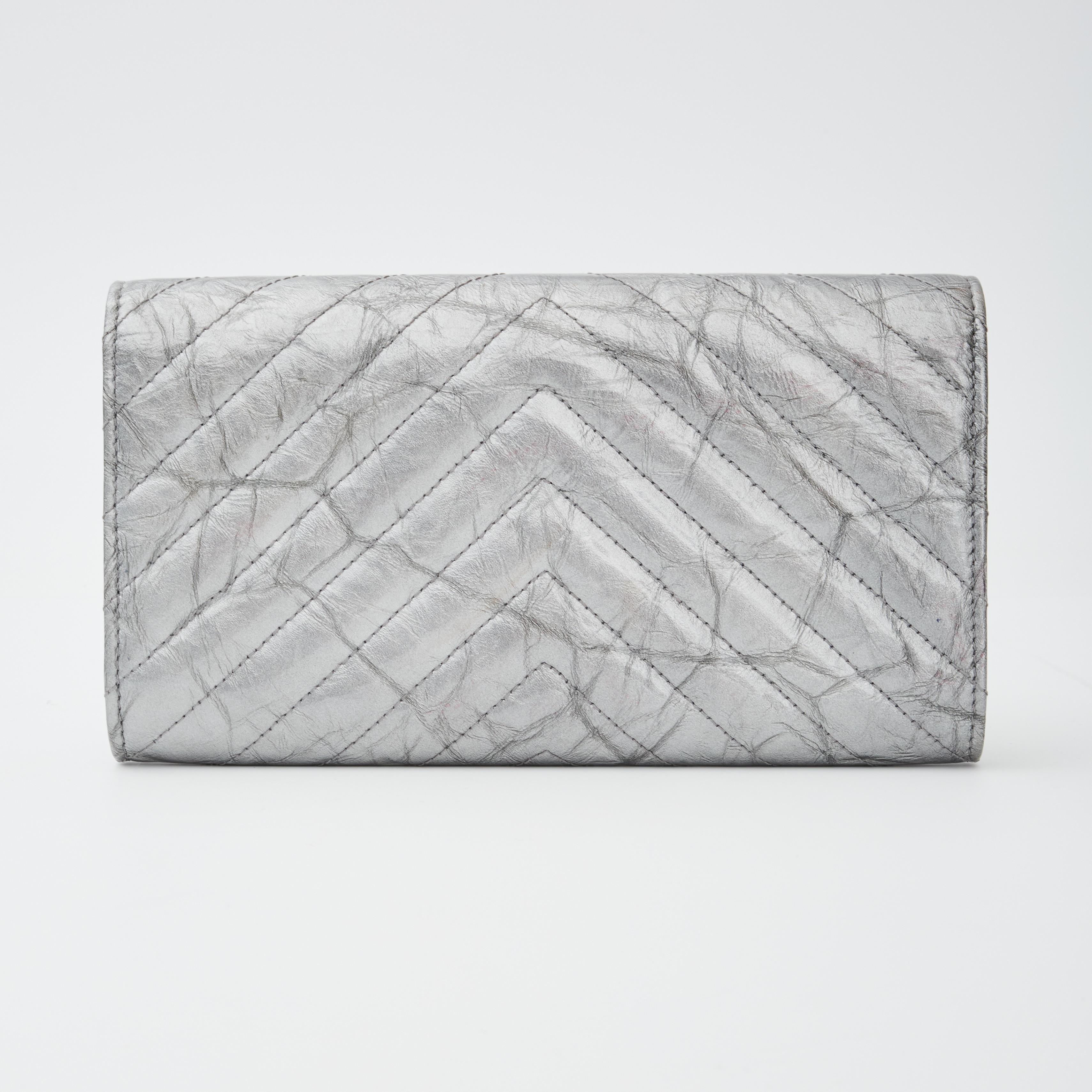 This wallet is constructed of a chevron quilted patent leather and features a small silver tone CC logo, a front flap, snap closure and a patronized interior. The interior has many card slots and a cash and coin compartment.

Chanel reference