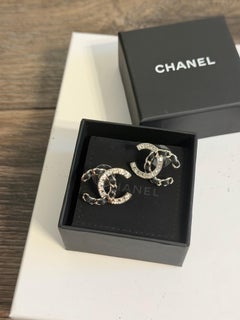 Pendientes de botón llamativos de Chanel con cristal plateado y cuero negro con el logotipo CC