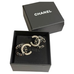 Pendientes de botón llamativos de Chanel con cristal plateado y cuero negro con el logotipo CC