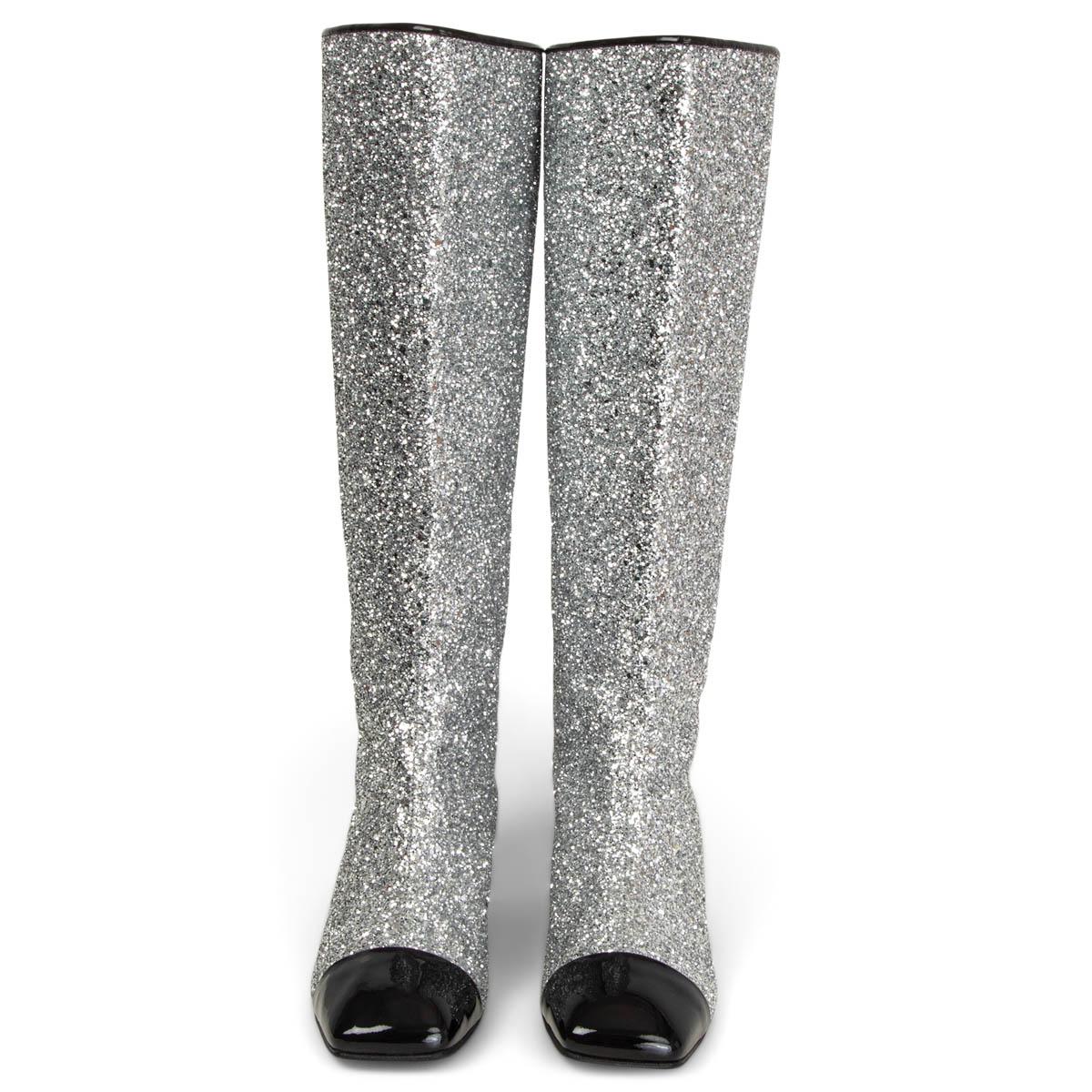 100% authentic Chanel boots in silver glitter featuring a black patent leather block heel and square cap toes. They have been adorned with the iconic CC logo at the top and come equipped with comfortable leather-lined insoles. Brand new. Rubber sole