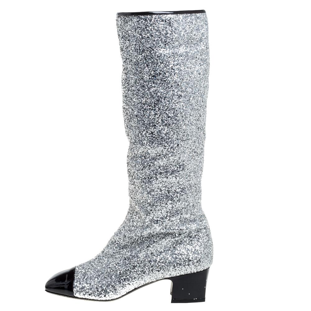 These Fantasy knee boots from Chanel epitomize chic and effortless style. They come crafted from silver glitter and patent leather and feature square cap toes. They have been adorned with the iconic CC logo at the top and come equipped with