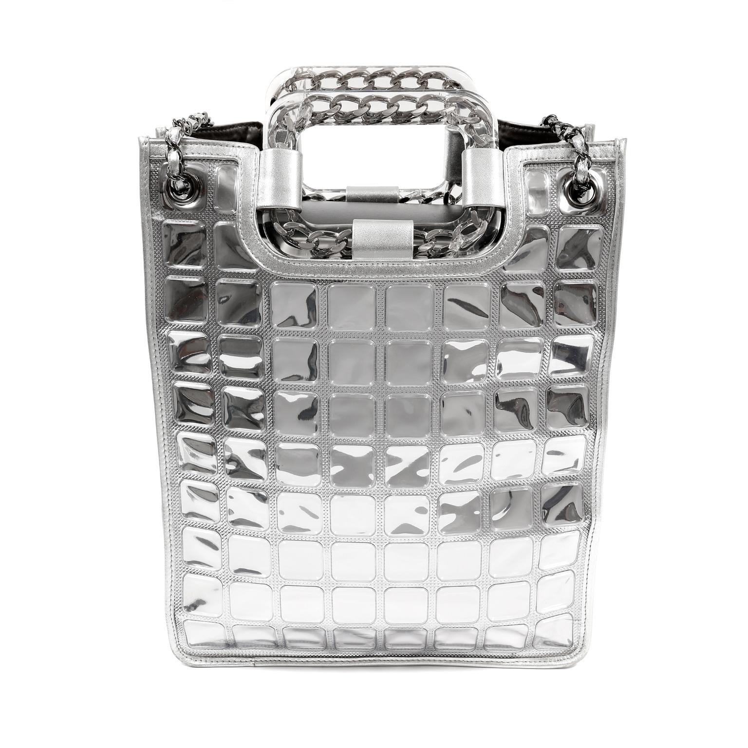 This authentic Chanel Silver Ice Cube Shopper is in pristine condition.  A rare collectible from the 2008 collection, it’s certain to add a “cool” vibe to any wardrobe. 
Metallic silver leather north south tote is covered in PVC “cubes.”  Clear