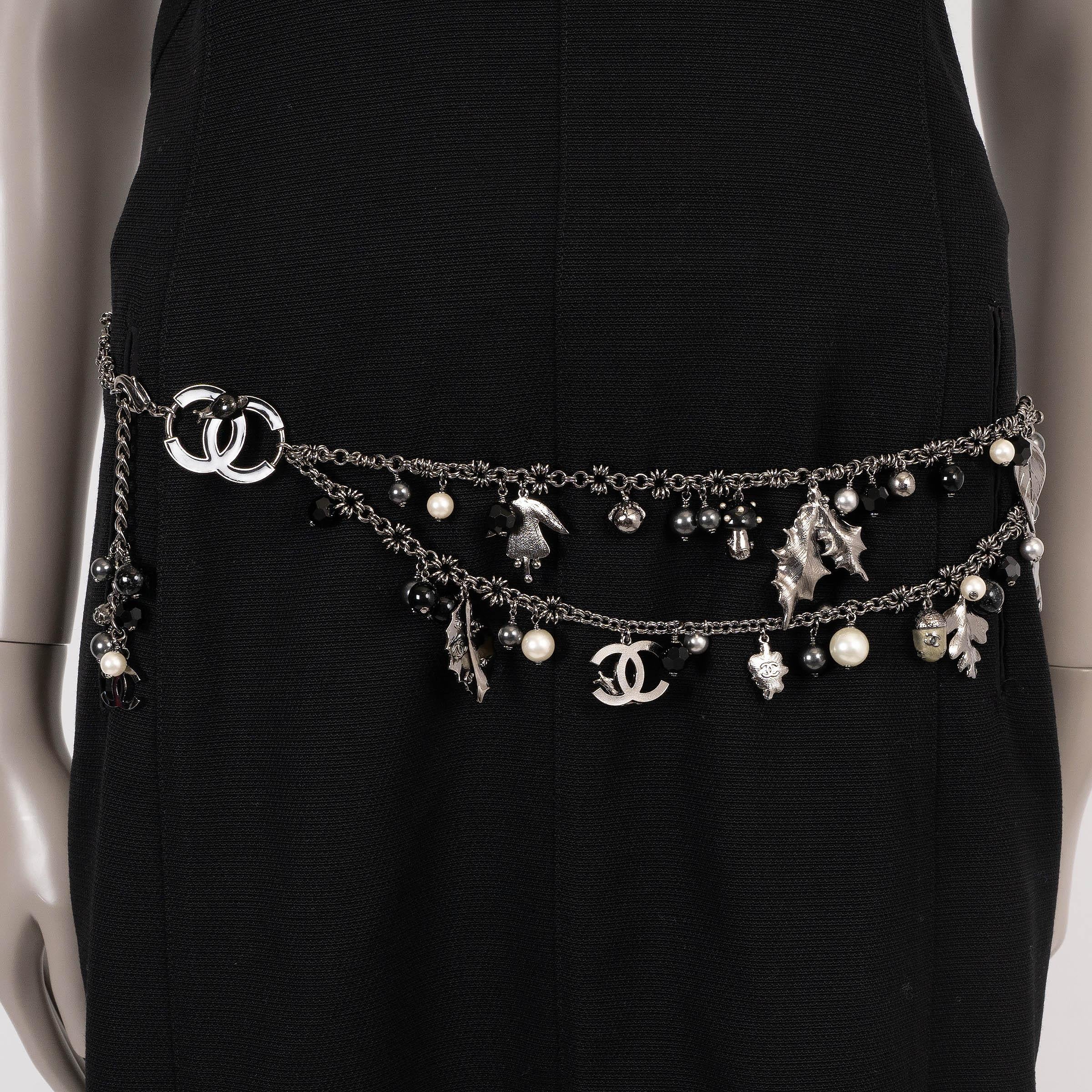Questa cintura Chanel autentica al 100% in catena argentata cattura l'essenza dell'autunno con i suoi stravaganti dettagli charme. Adornato con ghiande, foglie assortite e perle finte in nero, canna di fucile e bianco perlato, è rifinito con un logo