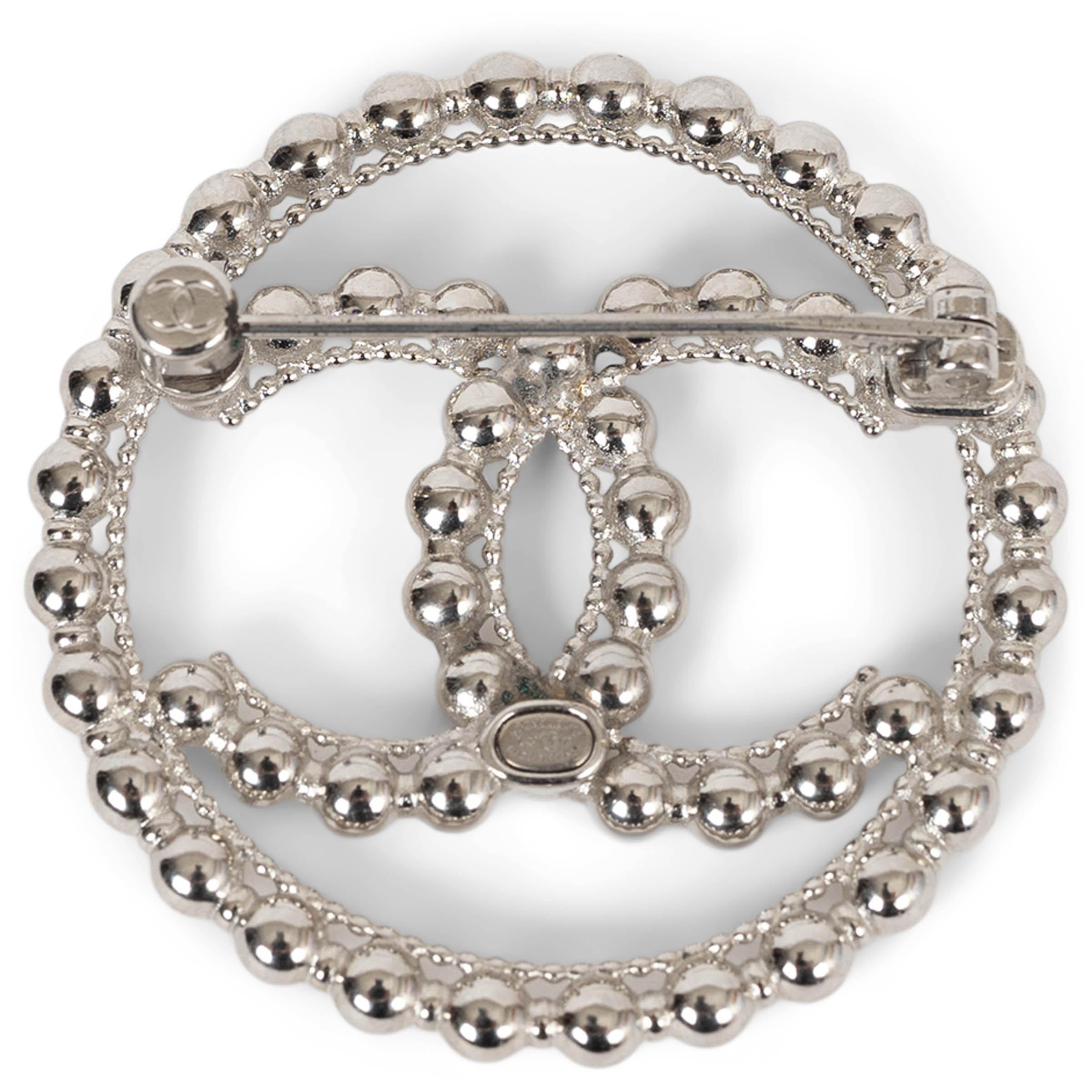 This 100% authentic Chanel round brooch in silver-tone metal is crafted from a continuous chain of polished metal beads, forming both the circular silhouette and the iconic interlocking CC at the center. A sculptural and modern interpretation of a