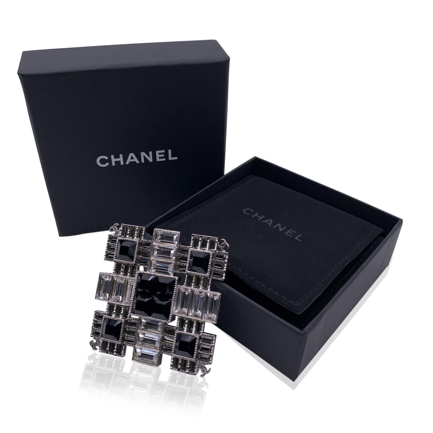 Chanel Square Pin Brooch. Silver metal with squared and rectangular crystals in black and clear/white colors. Small CC - CHANEL logos on corners. Safety pin closure. Measurements (HxL) 2 x 2 inches - 5.1 x 5.1 cm. 'CHANEL - G19 CC K- Made in Italy'