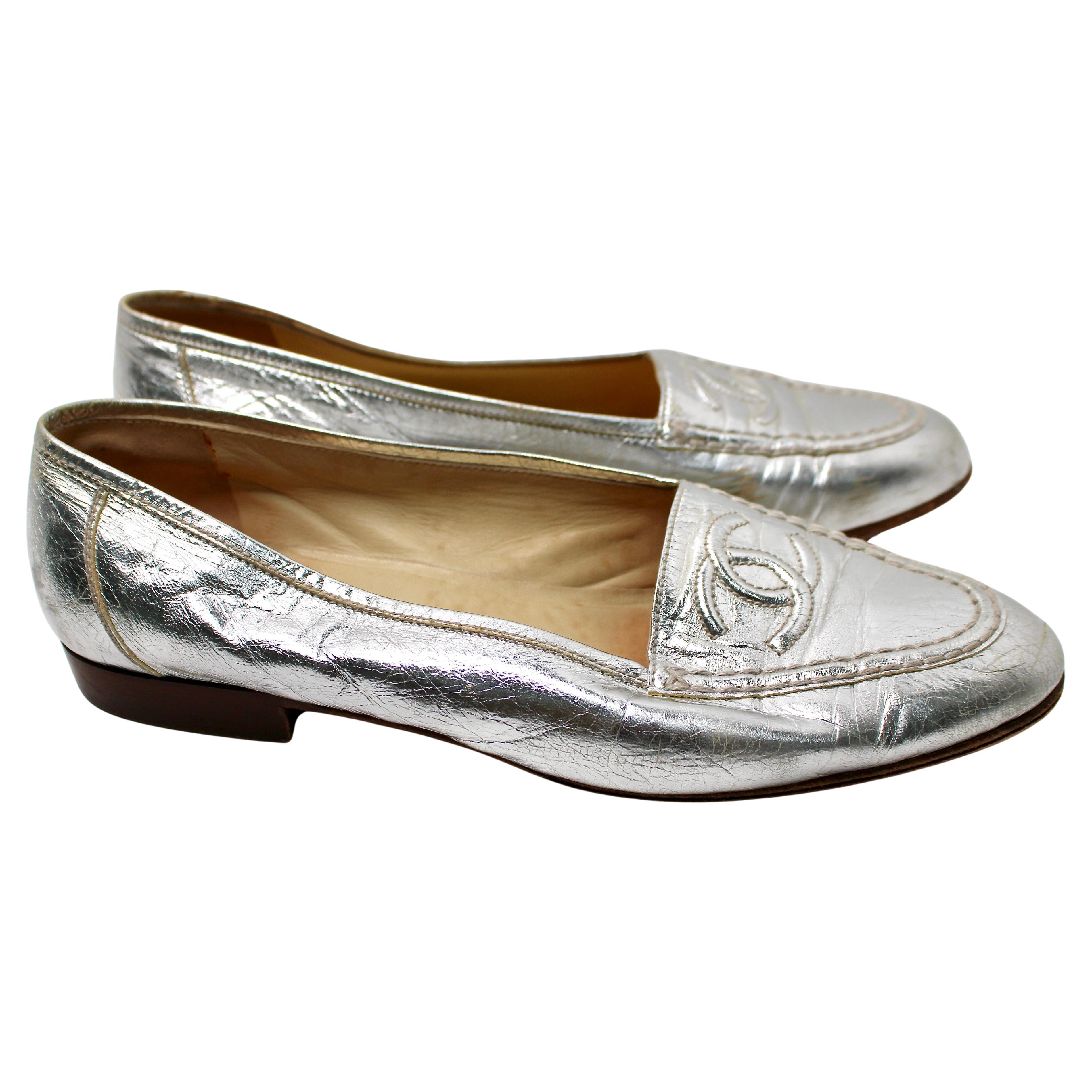 Estos emblemáticos mocasines Chanel de piel metalizada plateada con el logotipo CC entrelazado de los años 90 encarnan la elegancia y el lujo atemporales. Fabricados en piel metalizada de alta calidad, estos mocasines llevan el característico