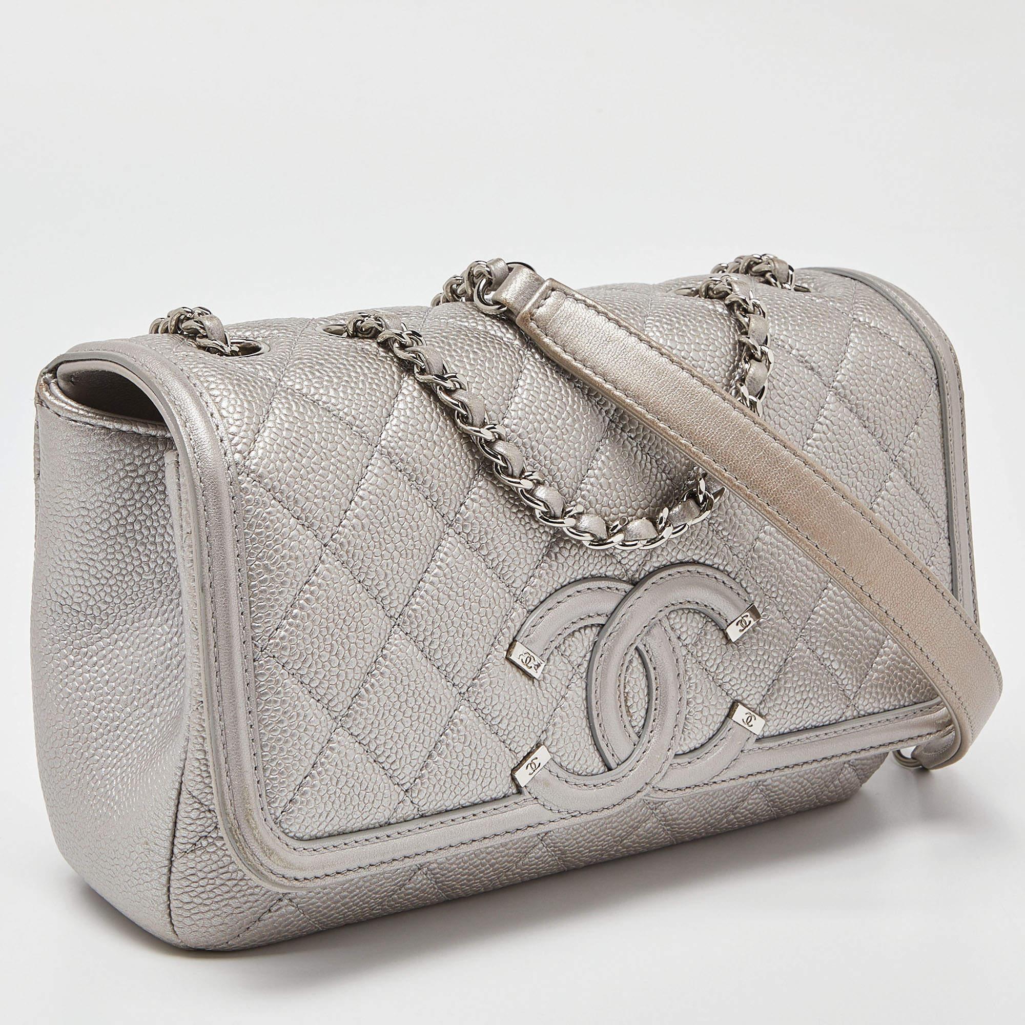This Filigree Flap bag from Chanel exudes the right amount of class and elegance. Crafted from silver Caviar leather, this bag is adorned with a 60 cm strap and silver-toned hardware. It has a leather-lined interior. Make this Chanel bag yours today