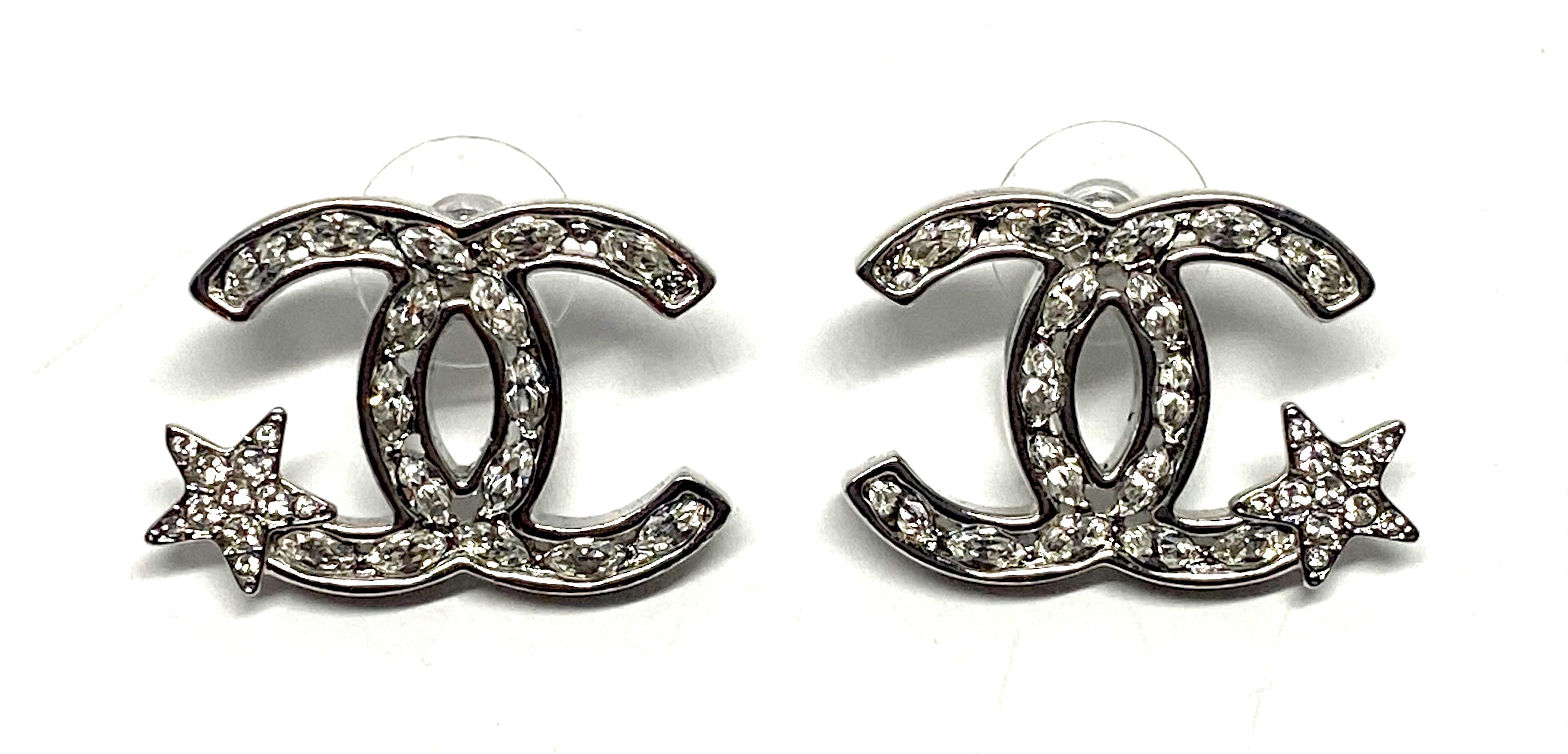 A fabulous pair of rhodium plate and rhinestone Chanel interlocking CC logo pierced earrings with star accent from the Spring 2020 collection. Each pierced earring measures 1.13 inches wide and .75 of an inch tall. The interlocking CCs are set with