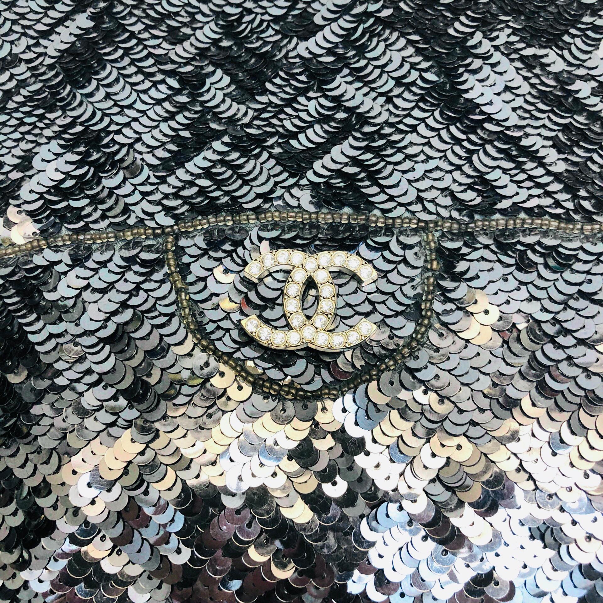 - Chanel silver sequins and silk clutch handbag. 

- Silver toned Hardware

- Open top and flat handles

- Satin Lining.

- Size: 20cm L x 0.3cm W x 16cm H. Handle Drop: 14cm. 