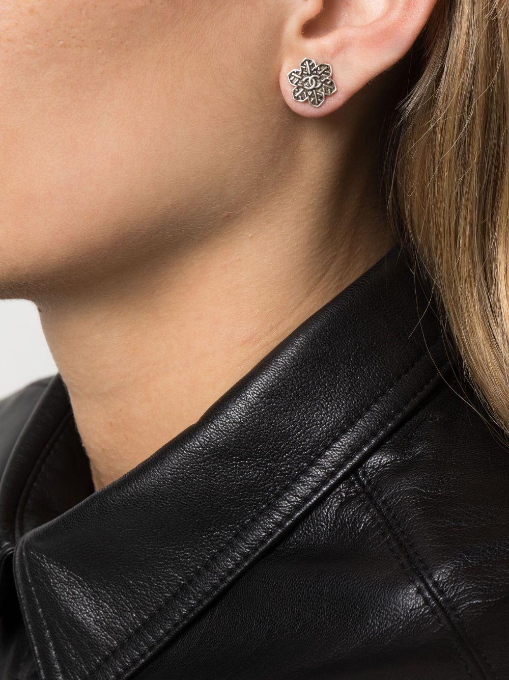 Silberfarbene Chanel Schneeflocken-Ohrringe mit folgenden Eigenschaften: Schneeflockenmotiv, charakteristisches, ineinandergreifendes CC-Logo, Stiftverschluss, für durchstochene Ohren, Plakette auf der Rückseite.
CIRCA 2019
Diese Ohrringe werden als