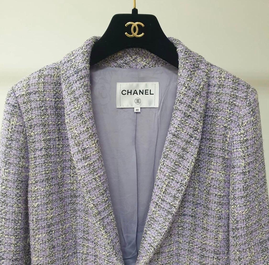Chanel lavender long sleeve tweed jacket with dual front patch pockets and front hook closure.
Shawl-collar. 
This item is previously worn and in very good condition.
Shell: Cotton/Polyester/Nylon/Rayon
Lining: 100% Silk
 It is from the Airport