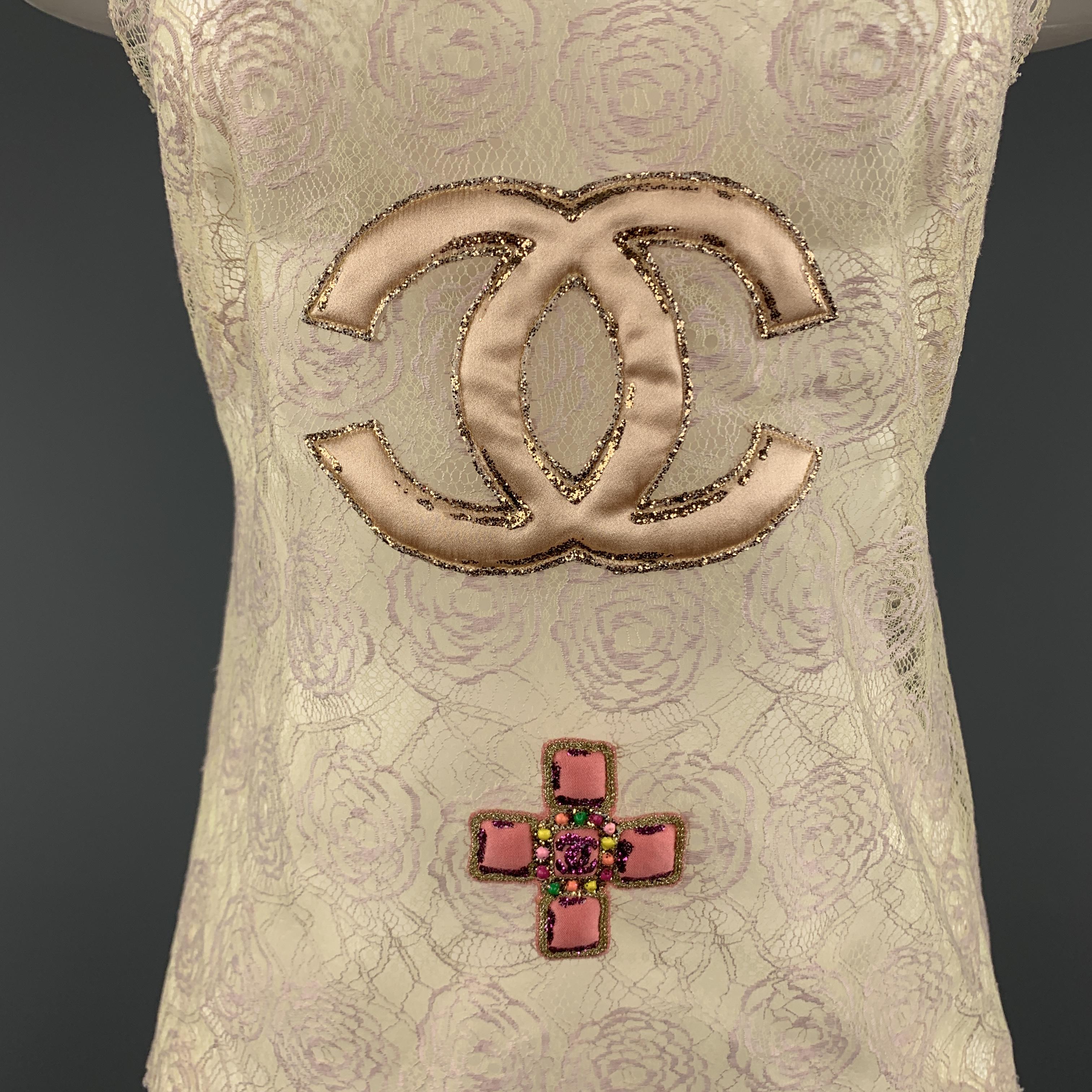Archive CHANEL Cruise 2004 Collection sleeveless top comes in beige and pink floral camellia lace with a scoop neck champagne satin CC logo and pink jewelry patches, detailed with glitter accents. Made in Italy.

Excellent Pre-Owned