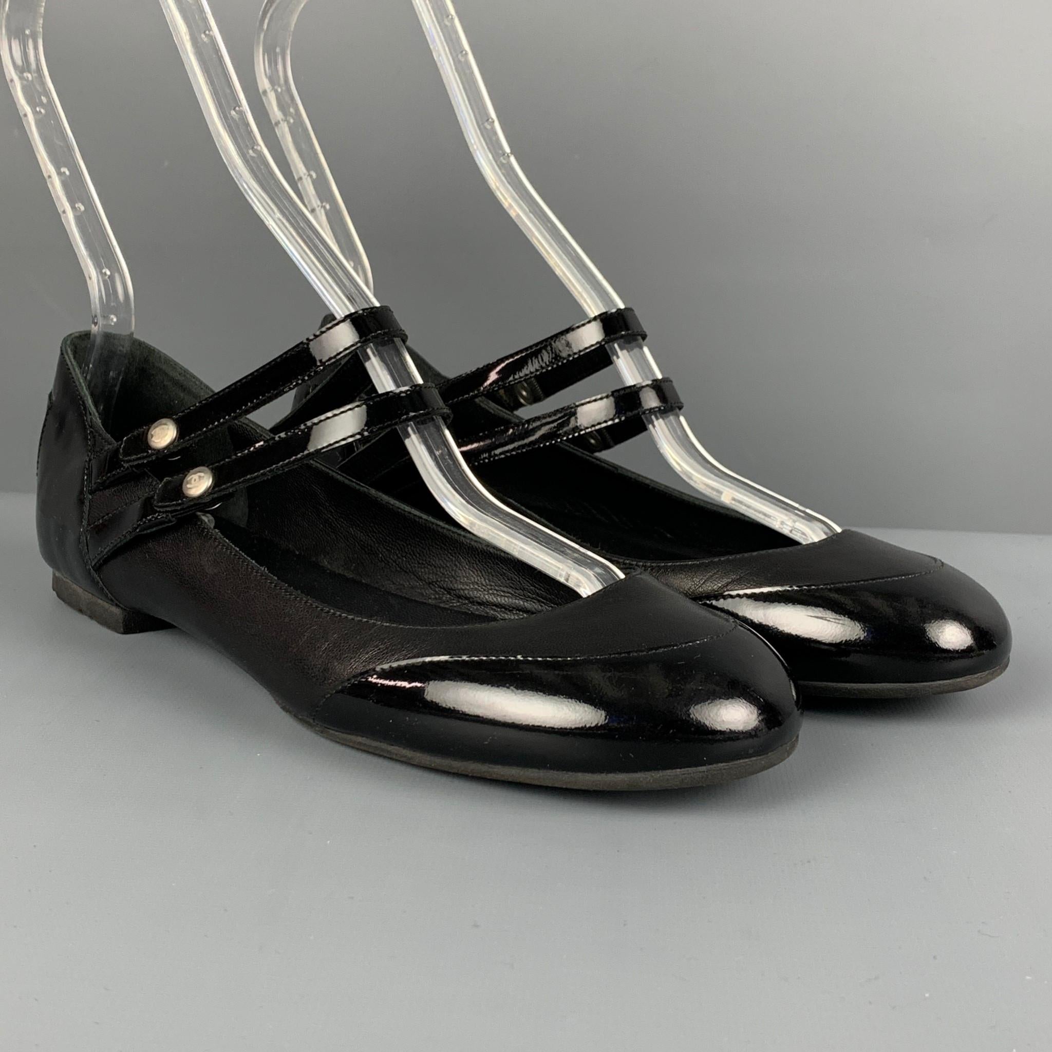 CHANEL flats comes in a black leather with a patent leather trim featuring a mary jane style, chanel logo buttons, and a double strap closure. Made in Italy. 

Very Good Pre-Owned Condition.
Marked: 38.5

Outsole: 10 in. x 3.25 in. 